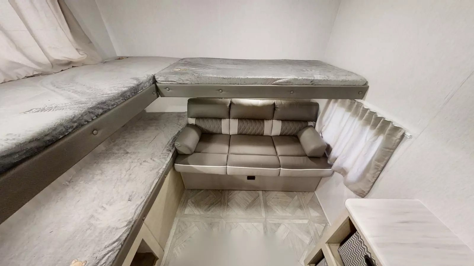 RV rental interior featuring bunk beds above a sofa, with patterned flooring. Compact and functional space for travel.. Forest River Wildwood X-Lite 2024