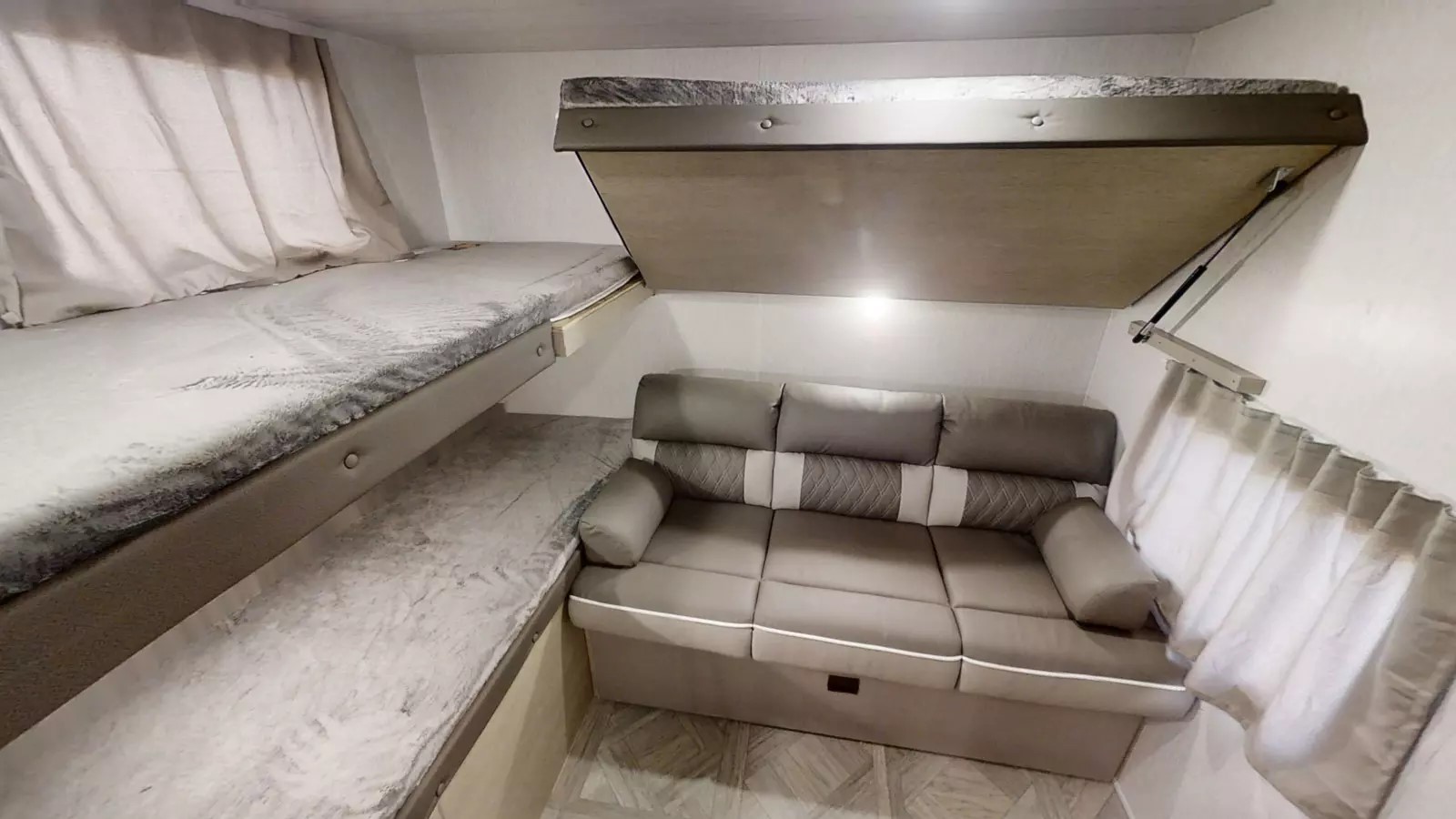 Cozy RV rental interior with bunk beds, a sofa, and an overhead drop-down bed. Ideal for family adventures.. Forest River Wildwood X-Lite 2023