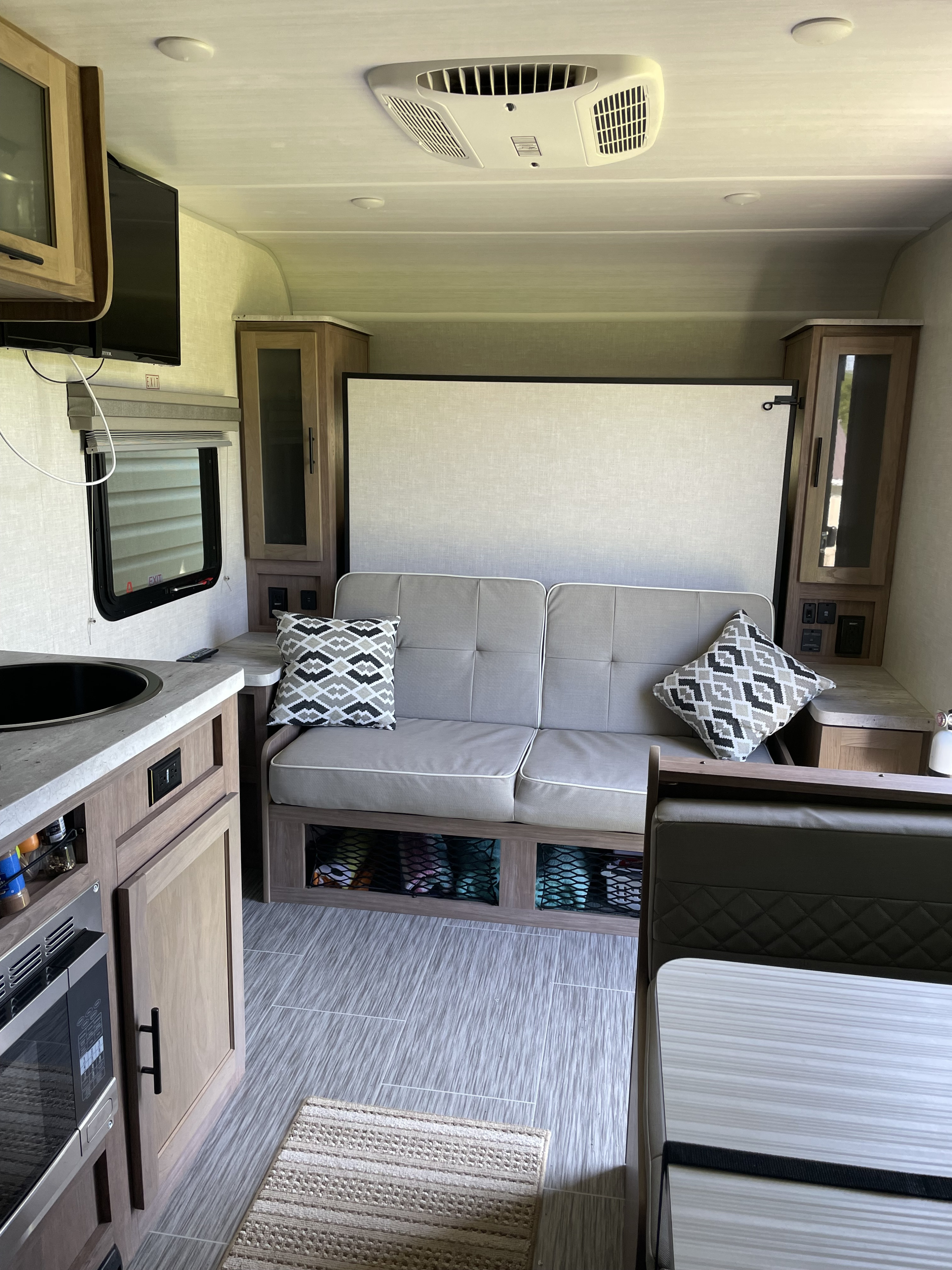 Modern RV rental interior: cozy living area with kitchenette, sofa, and a hidden convertible bed.. No Boundaries 19 2022