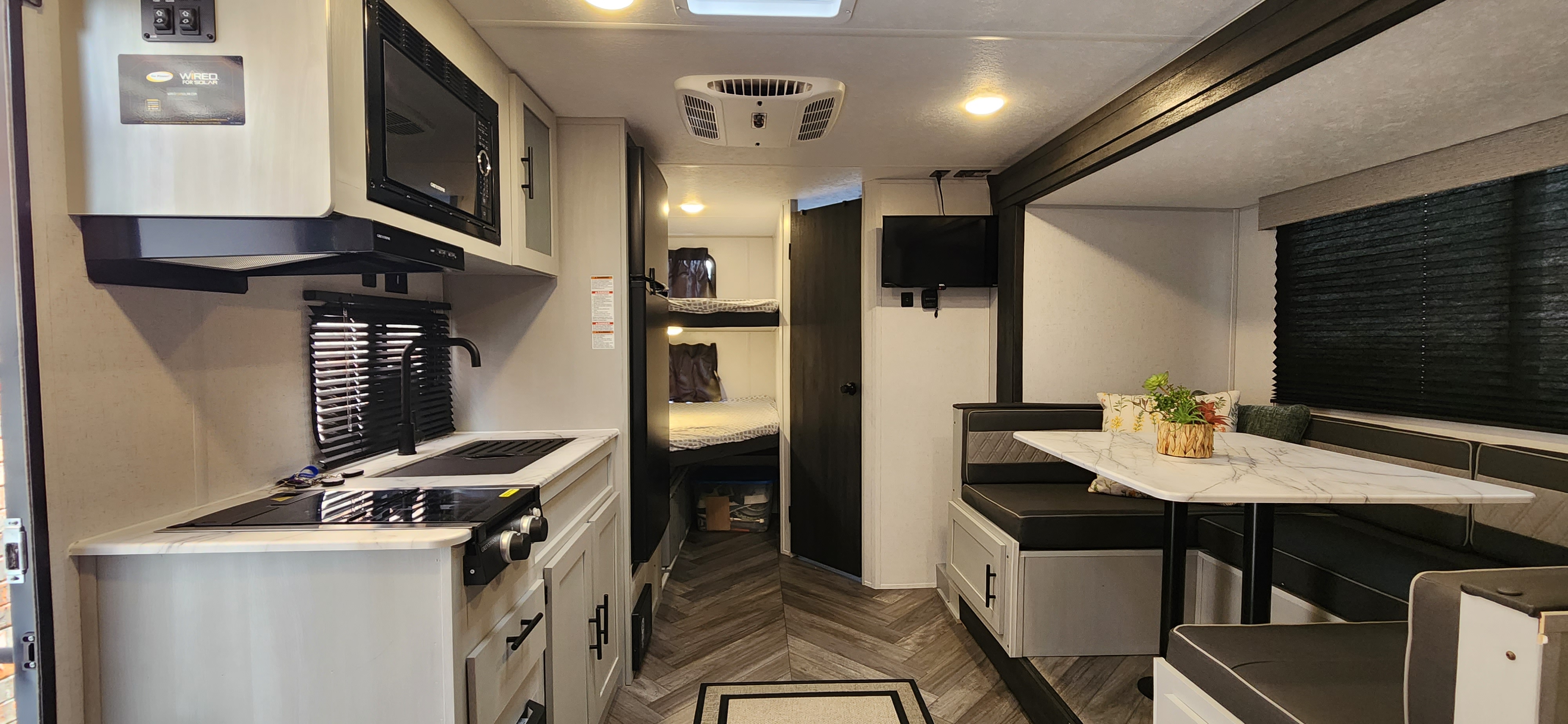 Explore this RV rental's well-equipped interior: kitchen, dining booth, TV, and bunk beds. Ideal for travel trailer adventures.. Forest River Salem FSX 2022