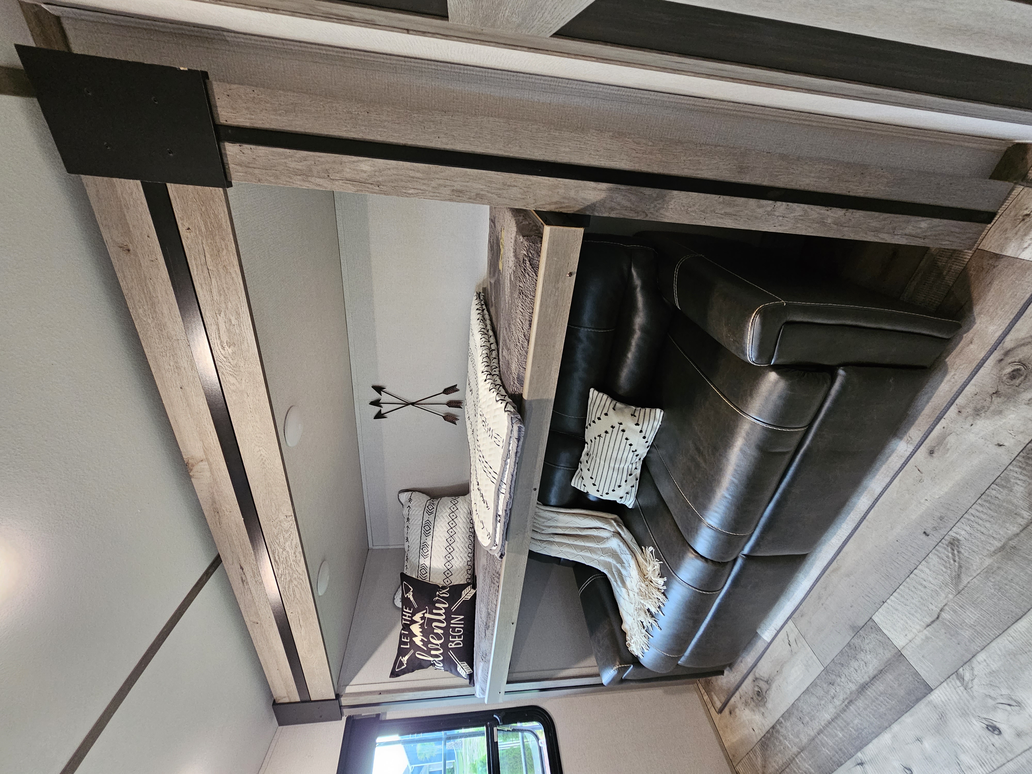 Inside a cozy RV rental. Features a dark leather sofa, patterned pillows, modern wood accents, and a bright living area.. Keystone RV Outback 2021