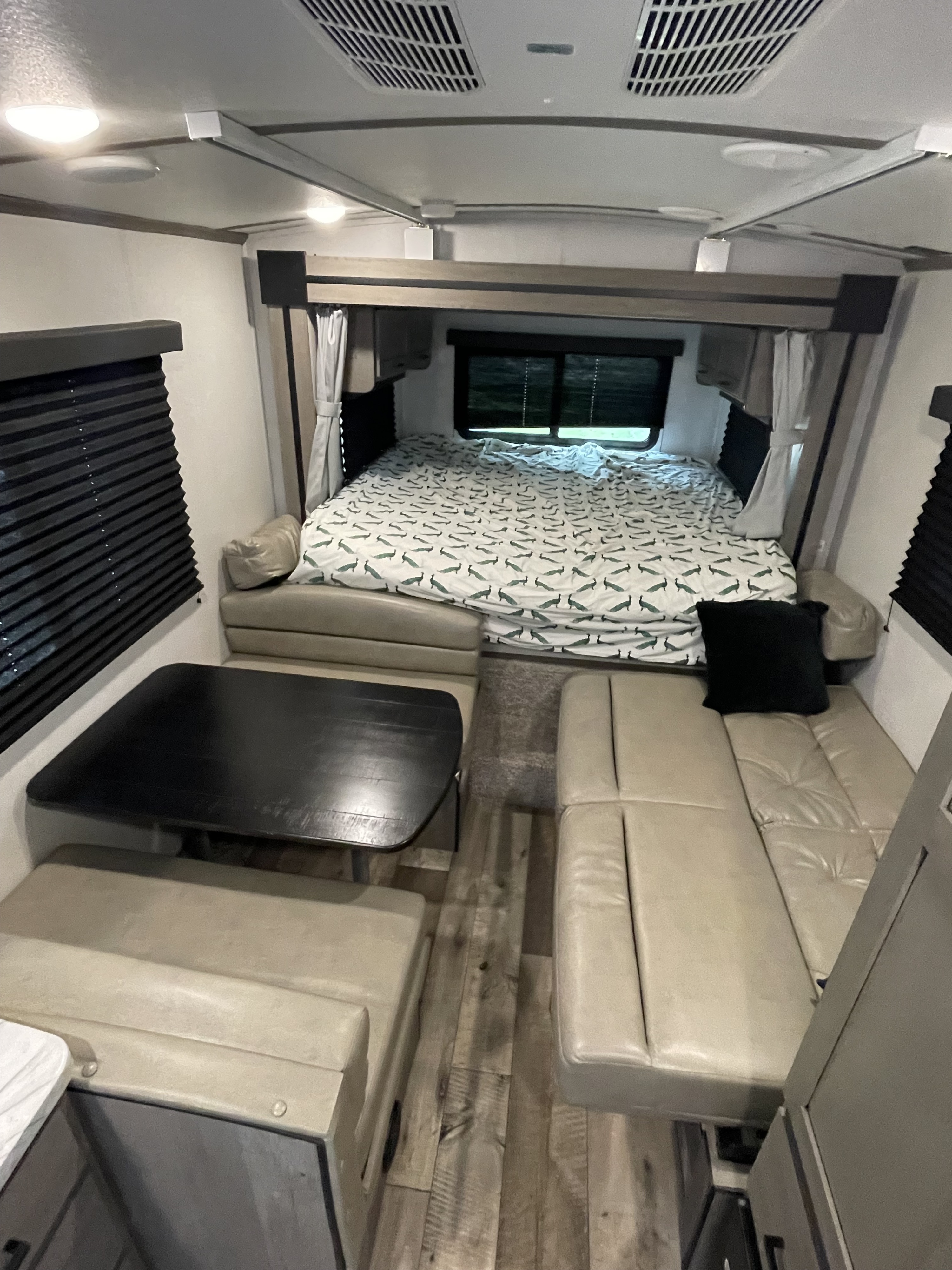 Cozy rv rental interior featuring a practical dinette, a bedroom with a unique peacock-patterned bed, and comfortable lounge seating.. Keystone RV Outback Ultra-Lite 2021