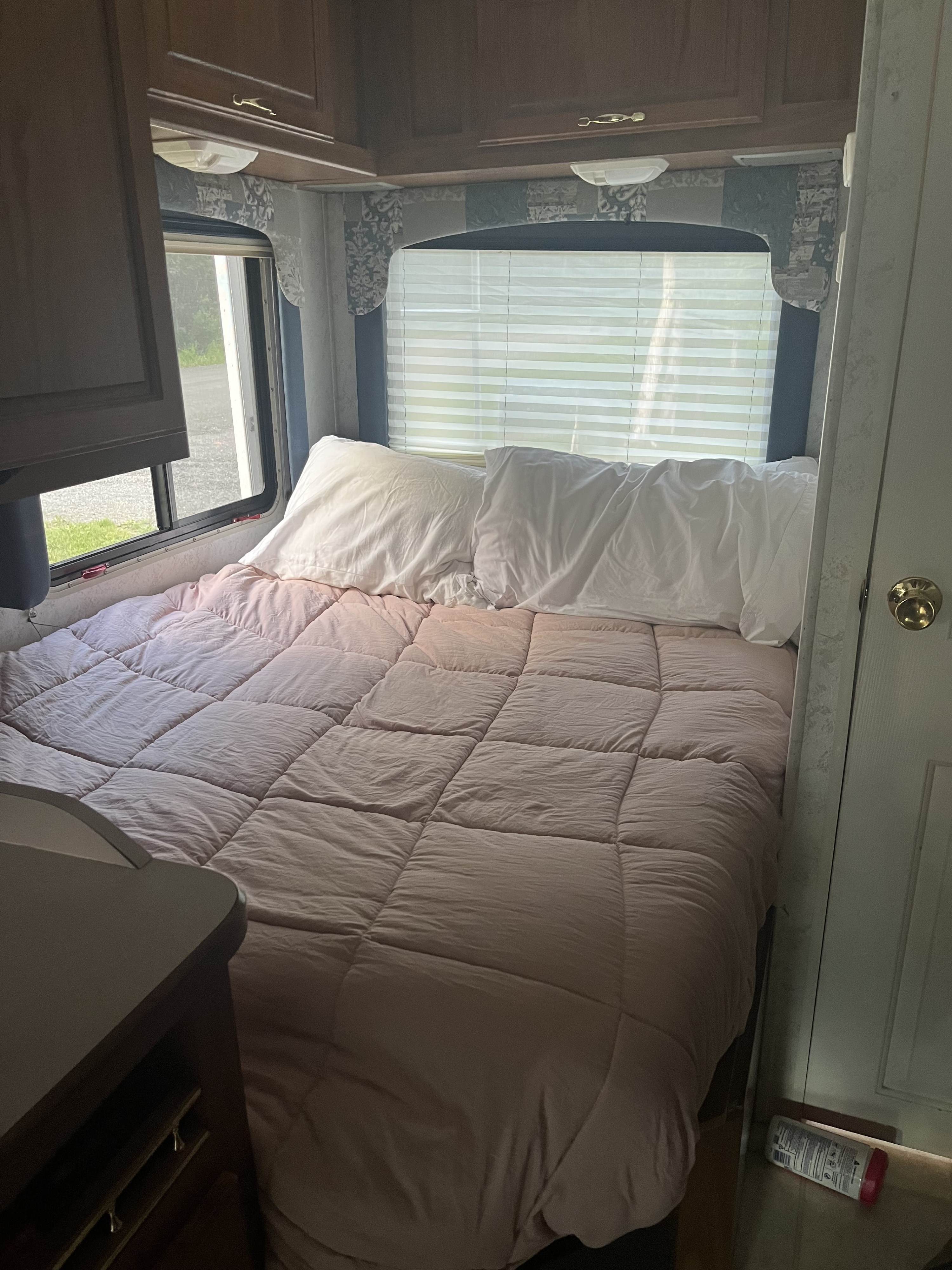 Cozy RV rental bedroom with a comfy bed, white pillows, and a window with blinds, perfect for an adventure.. Dutchmen Express 2001