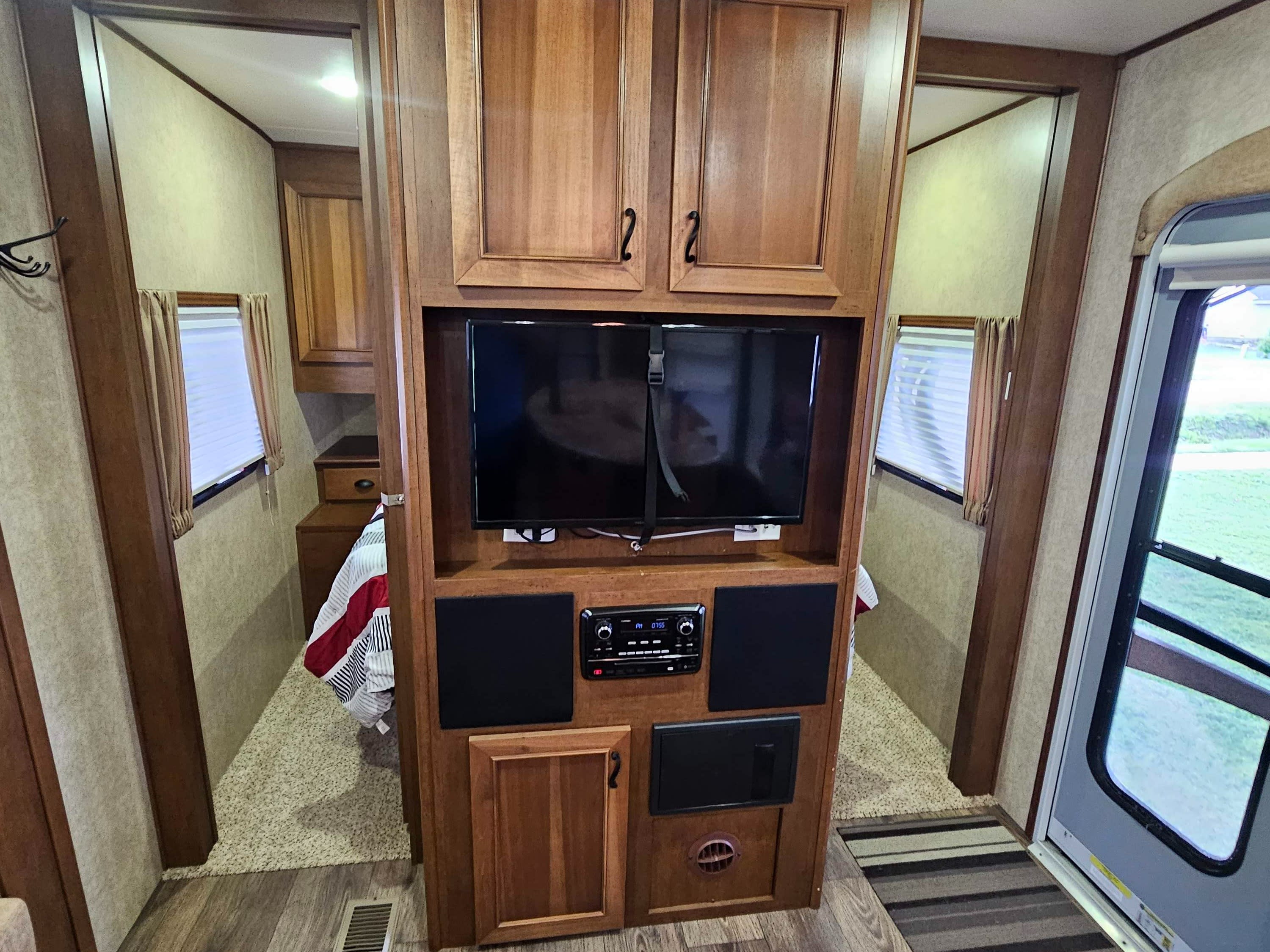 This inviting RV rental offers a comfortable bedroom with a window, entertainment system, and accessible entry, ready for your next getaway.. Open Range RV Light 2014