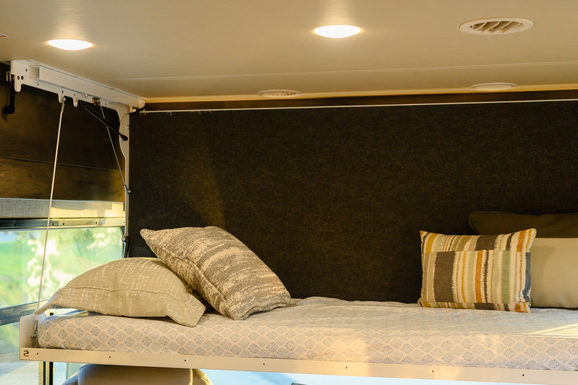 Explore an RV rental with this elevated bunk bed, featuring soft pillows, overhead lights, and a scenic window view.. Tiffin Open Road 36UA 2023