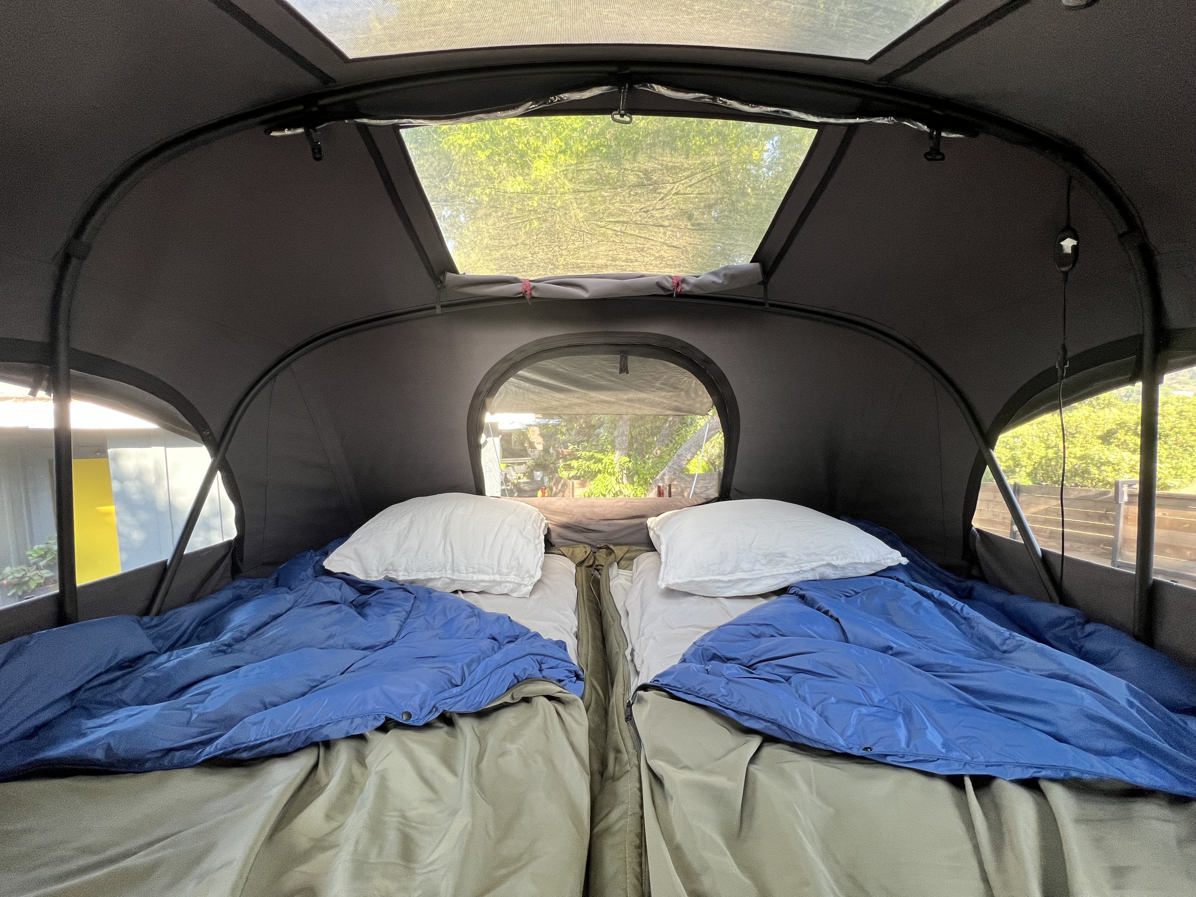 Cozy RV rental interior with two beds, ideal for camping adventures. Skylight and windows show nature.. Escapod Escapod Trailer 2023