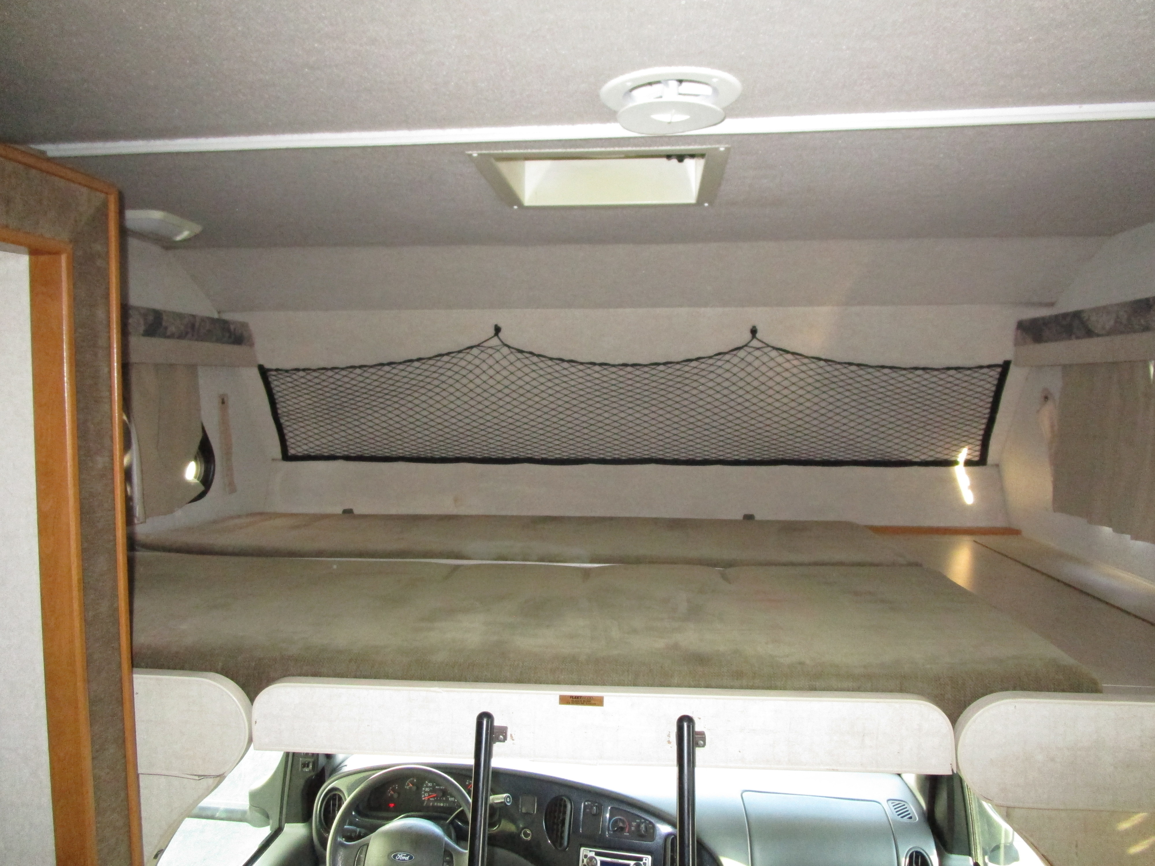 Spacious RV rental cab-over bunk with sleeping area, safety net, and visible cockpit. Perfect for travel.. Jamboree Jamboree Motorhome 2002