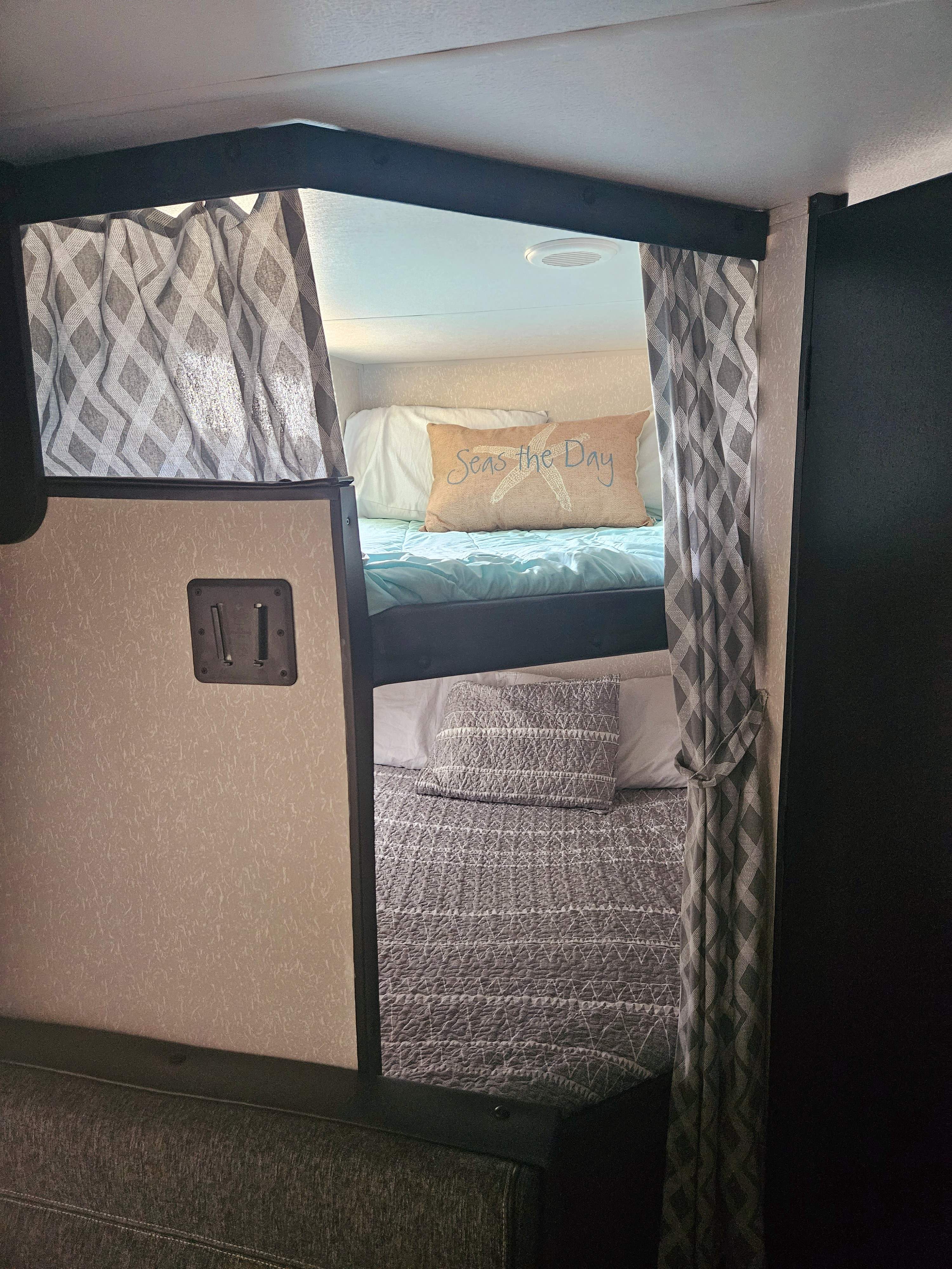 Cozy RV rental bunk beds with curtains & beach-themed pillow. Perfect sleeping area for your next road trip adventure!. Forest River Cherokee Grey Wolf Special Edition 2022
