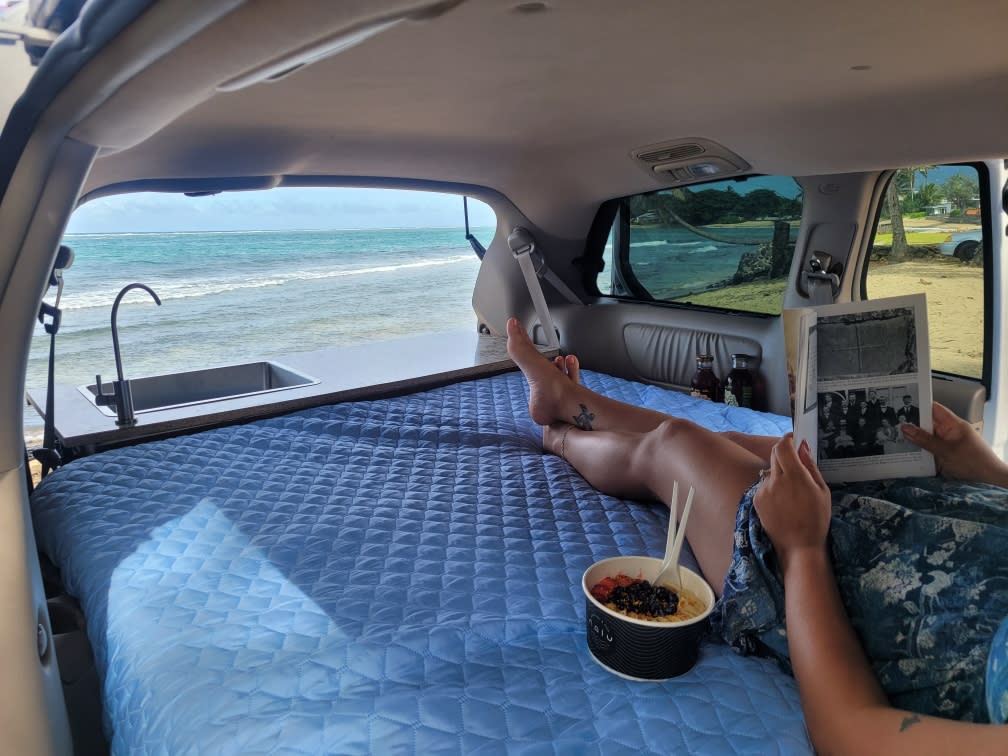 Enjoying a serene beach view from an RV rental's cozy bed, complete with a sink, while reading & snacking. Perfect campervan life.. Toyota Sienna 2008