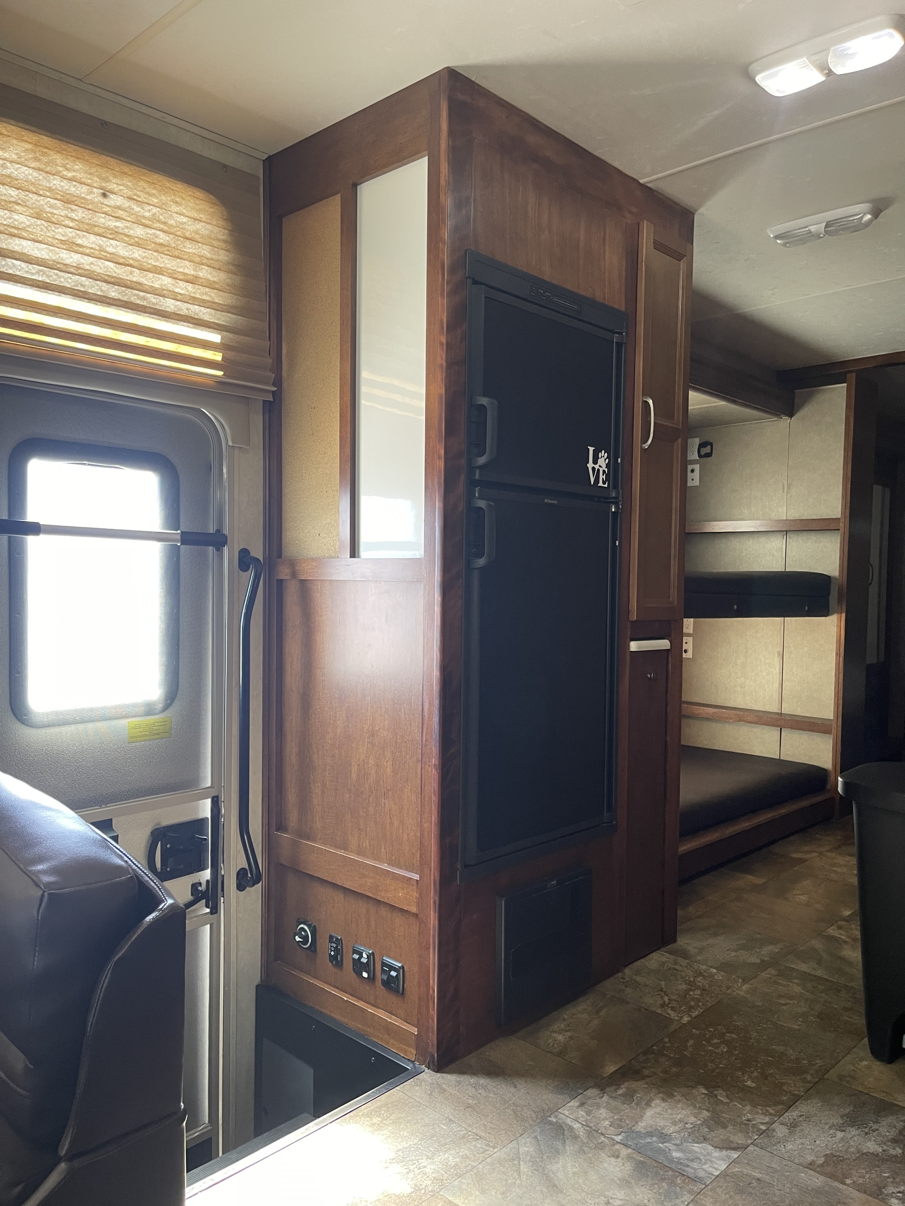 Step inside this spacious RV rental featuring a full-size fridge, wooden interior, comfortable bunk beds, and tiled floors.. Coachmen Pursuit 2014