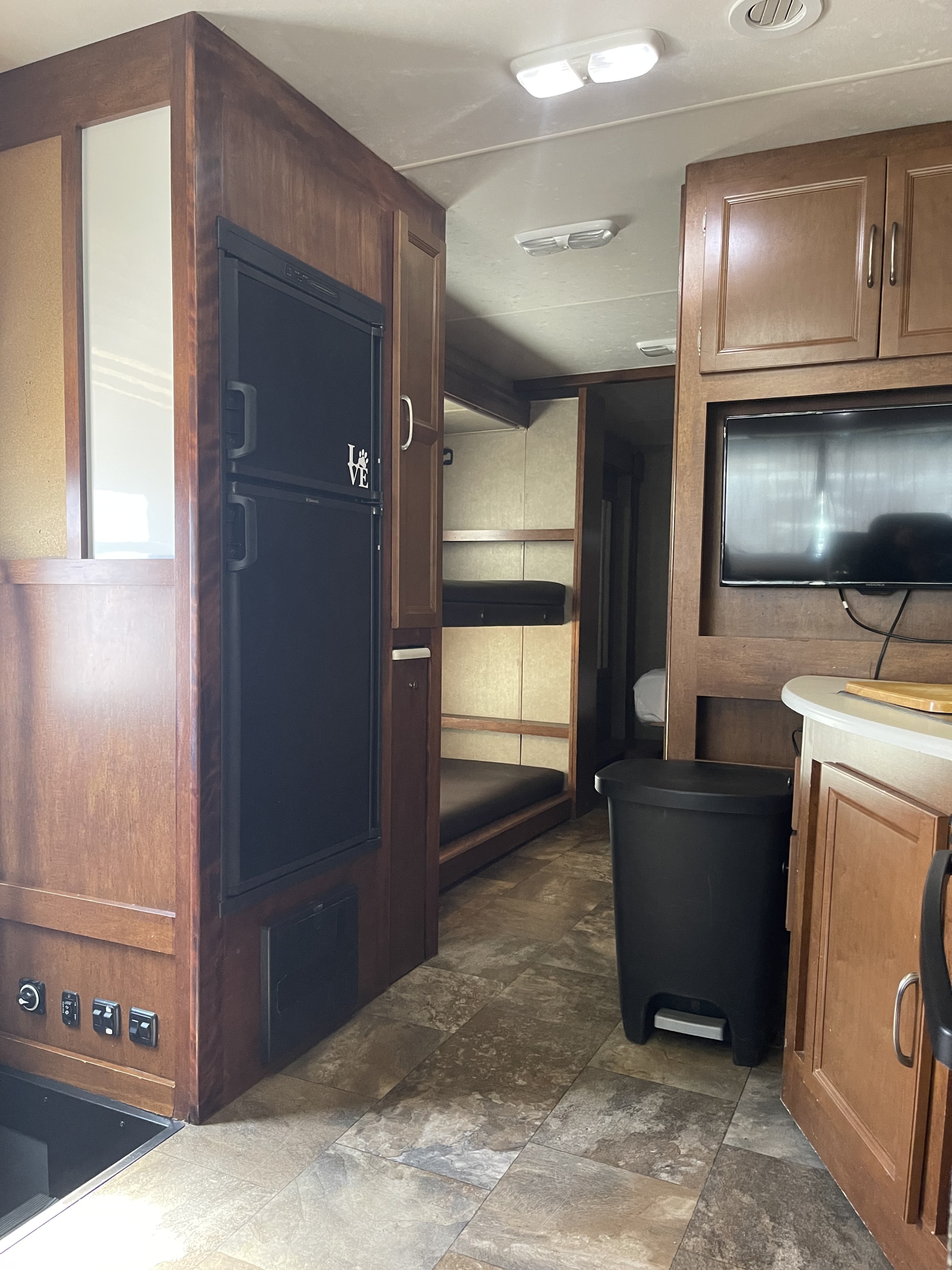 Step inside this RV rental, featuring a compact kitchen with a fridge, built-in bunk beds, and a living area with a TV.. Coachmen Pursuit 2014