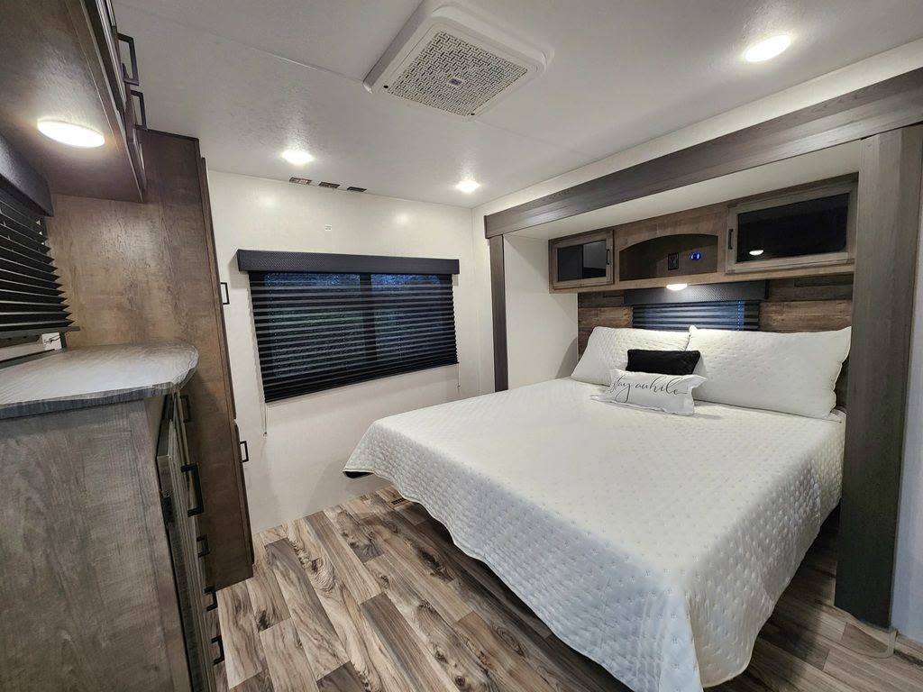 Experience comfort in this well-appointed RV bedroom. Ideal for your next rv rental getaway, featuring a cozy bed & storage.. SportTrek STT333VFK 2023
