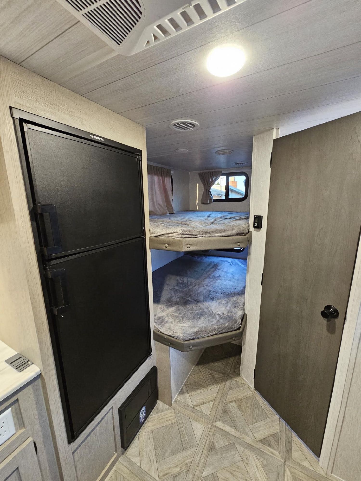 RV rental interior: black fridge on left, bunk beds, and light wood-patterned floor.. Forest River Salem Cruise Lite 2024