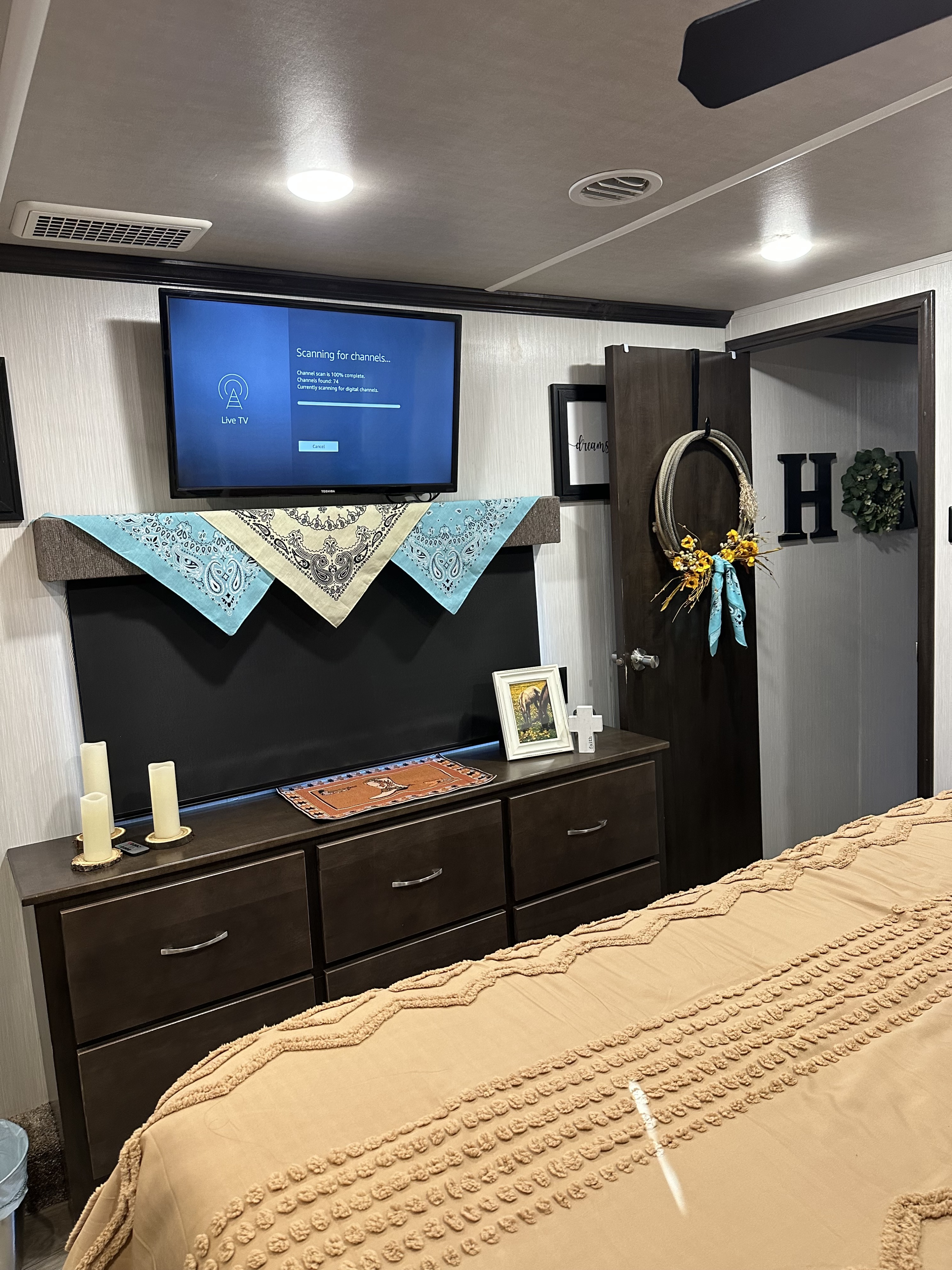 Inside a comfortable RV rental bedroom featuring a TV, dark wood dresser, and western-themed decor.. Cedar Creek Cedar Creek Fifth Wheel 2021