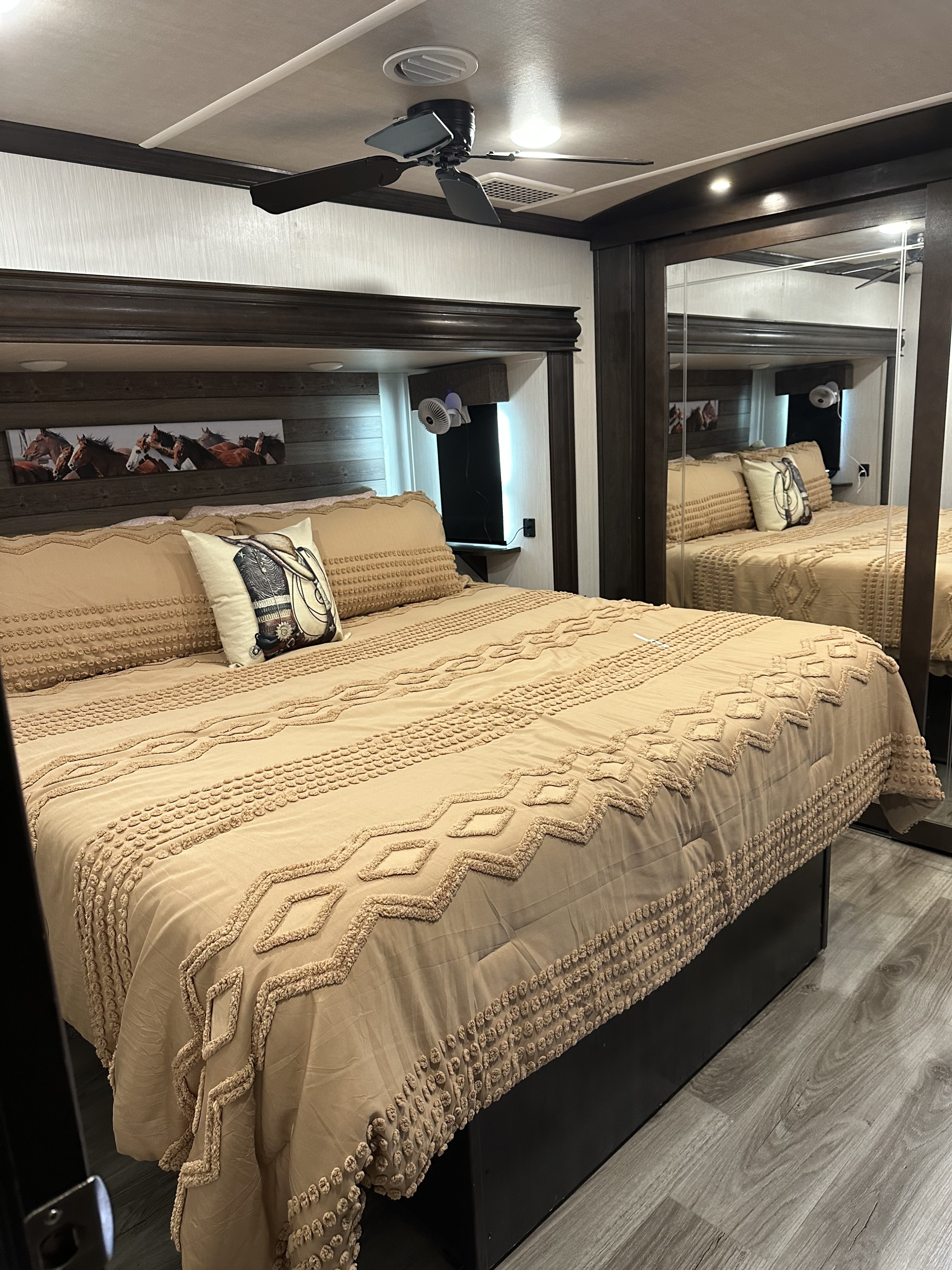 Inviting RV rental bedroom: large bed with patterned comforter, horse art, mirrored closet, fan & AC.. Cedar Creek Cedar Creek Fifth Wheel 2021