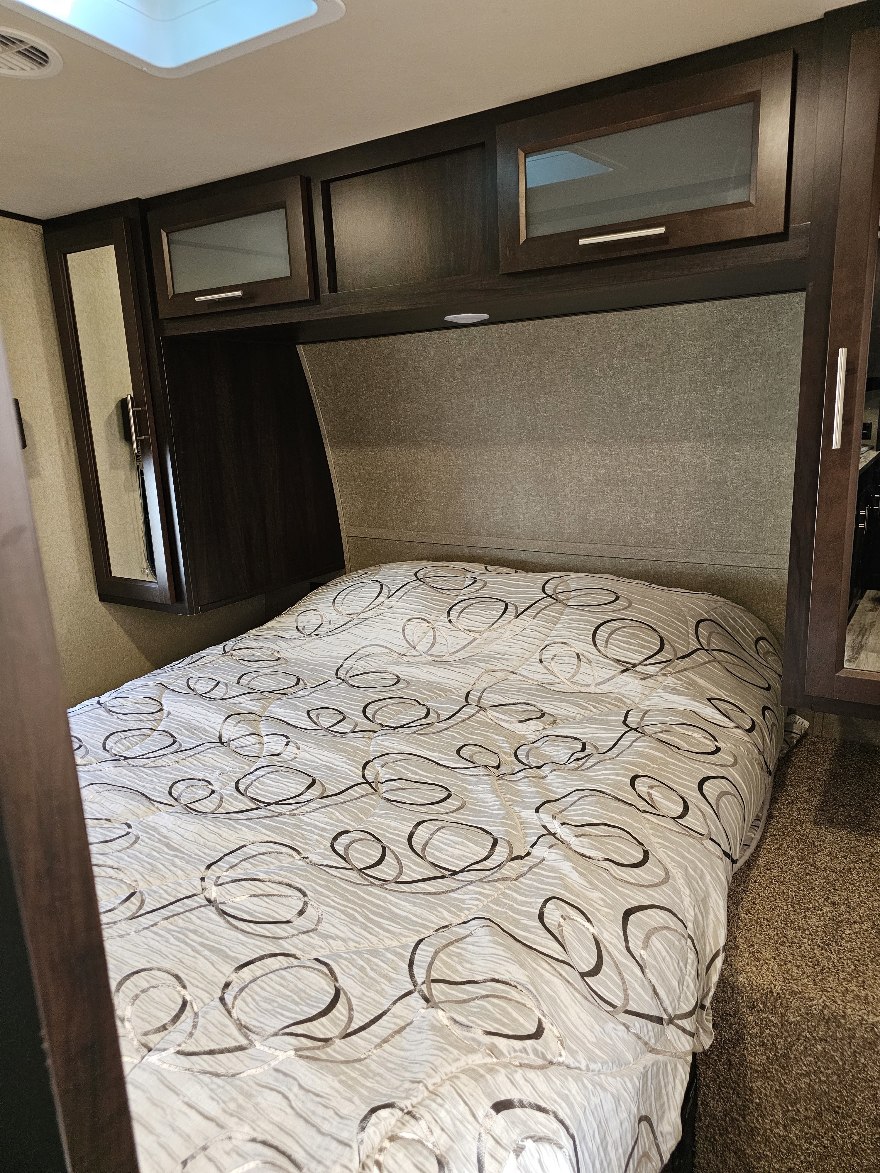 Comfortable RV rental bedroom with patterned comforter, dark cabinetry, and skylight. Relax while traveling.. Forest River XLR Hyperlite 30HDS 2017