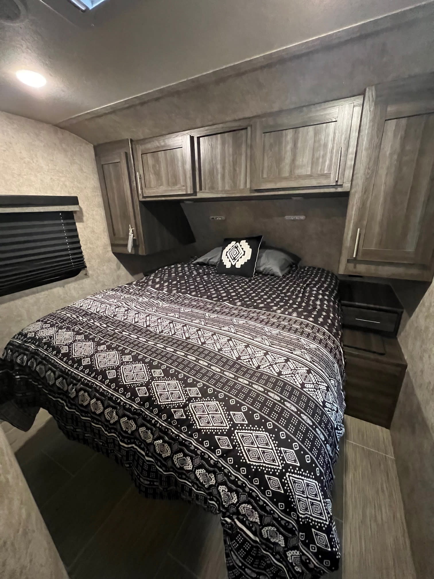 Cozy RV rental bedroom with a queen bed, black & white geometric comforter, ample storage cabinets, and a window blind.. Highland Ridge RV Open Range Ultra Lite 2019