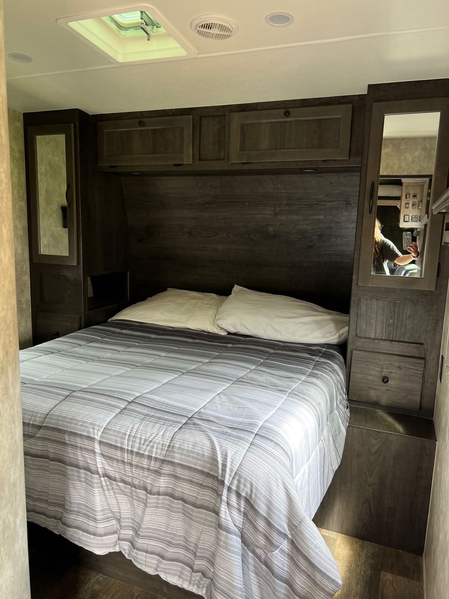 Inside an RV rental: a compact bedroom with a bed, dark wood-toned cabinetry, mirrored wardrobes, and overhead storage.. Eclipse Recreational Vehicles Iconic 2018