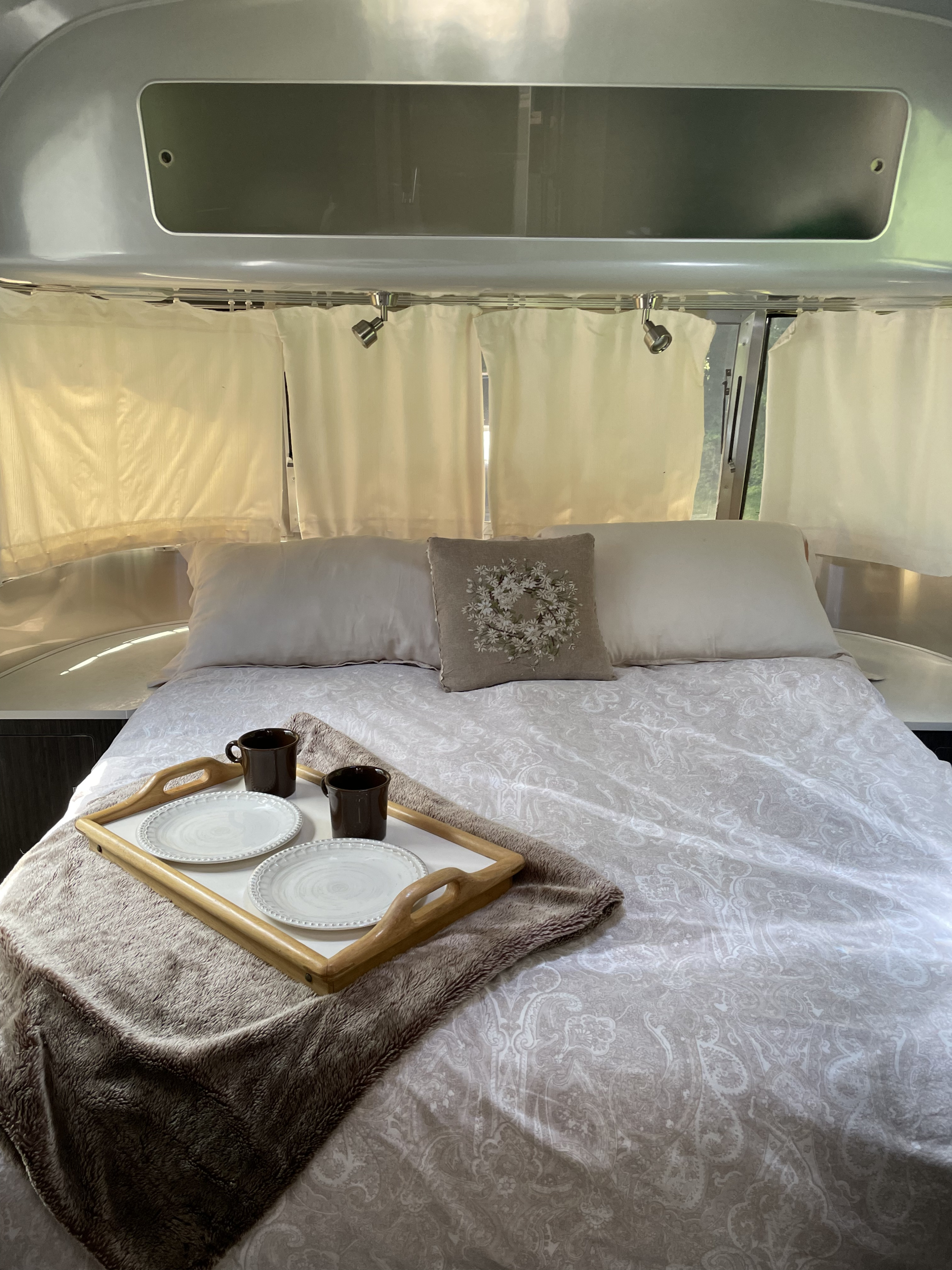 Cozy Airstream RV rental bedroom: A comfortable bed with breakfast tray, pillows, and ambient lighting.. Airstream International 2014