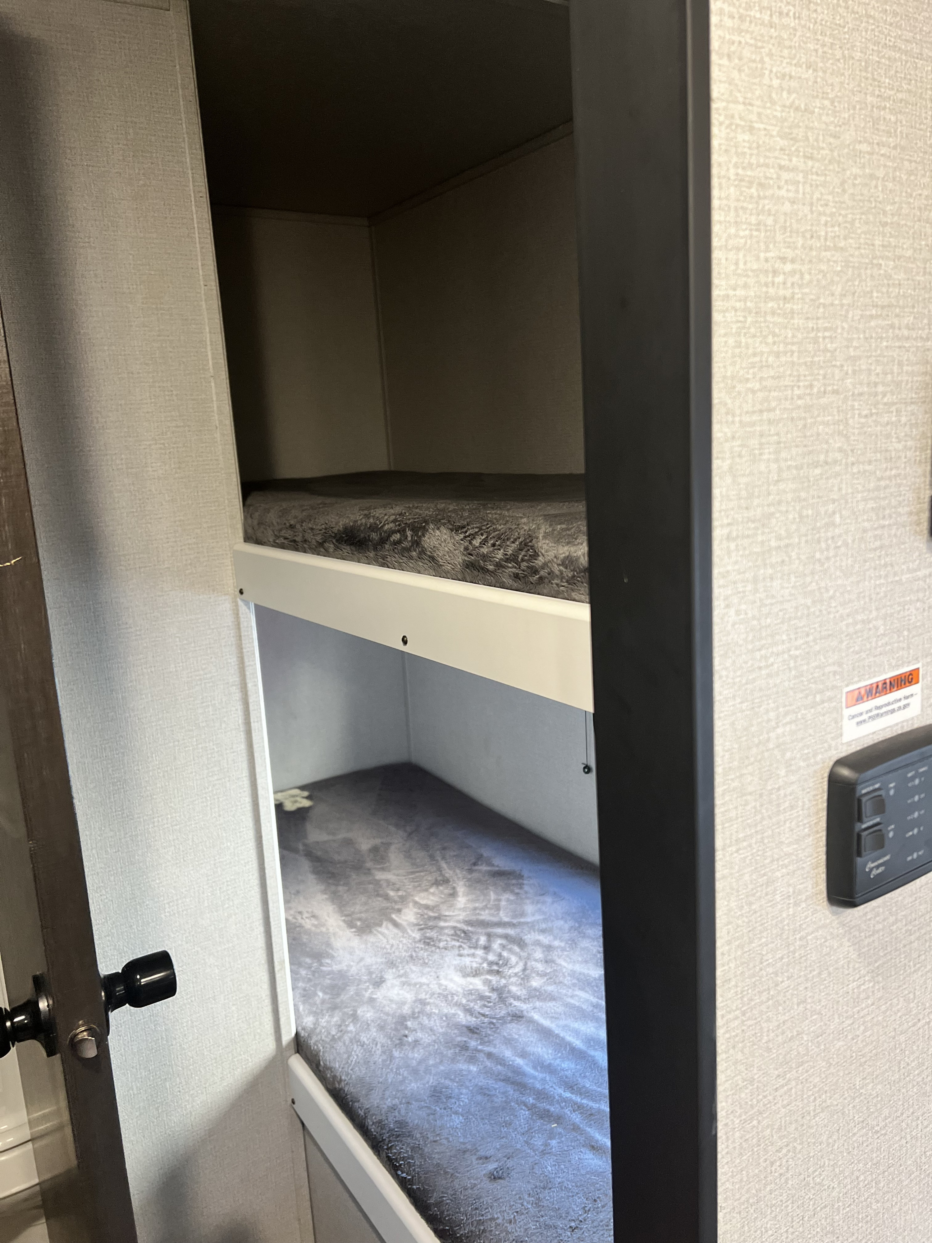 Inside an RV rental, showing two grey-matted bunk beds, a compact and practical sleeping solution.. Keystone RV Hideout 2021
