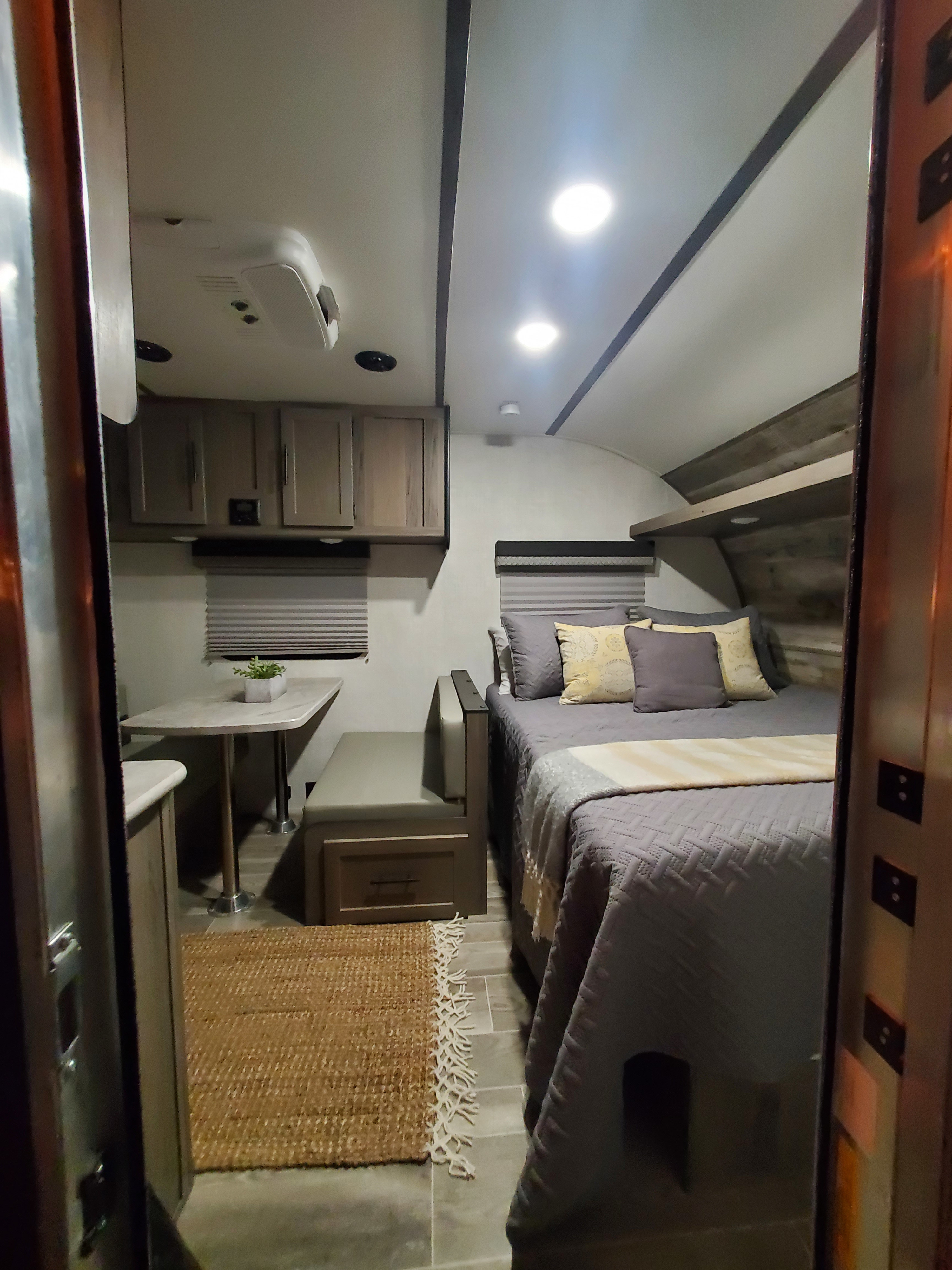 View inside a cozy RV rental, featuring a comfortable bed, dining table with seating, and modern cabinets.. Gulf Stream Ameri-Lite Super Lite 2022