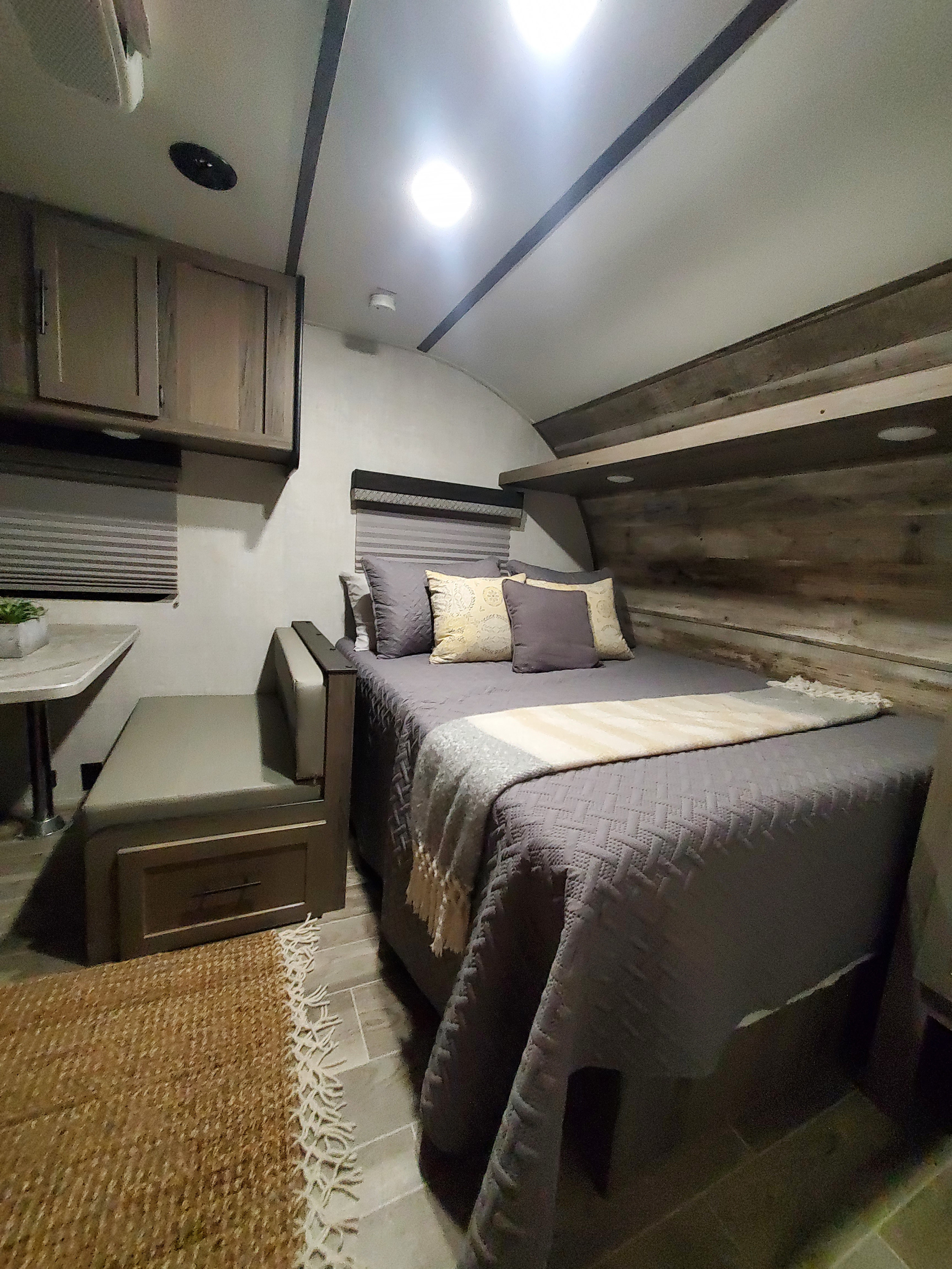 Cozy rv rental bedroom and dining area with a comfortable bed, rustic accents, and smart storage solutions.. Gulf Stream Ameri-Lite Super Lite 2022