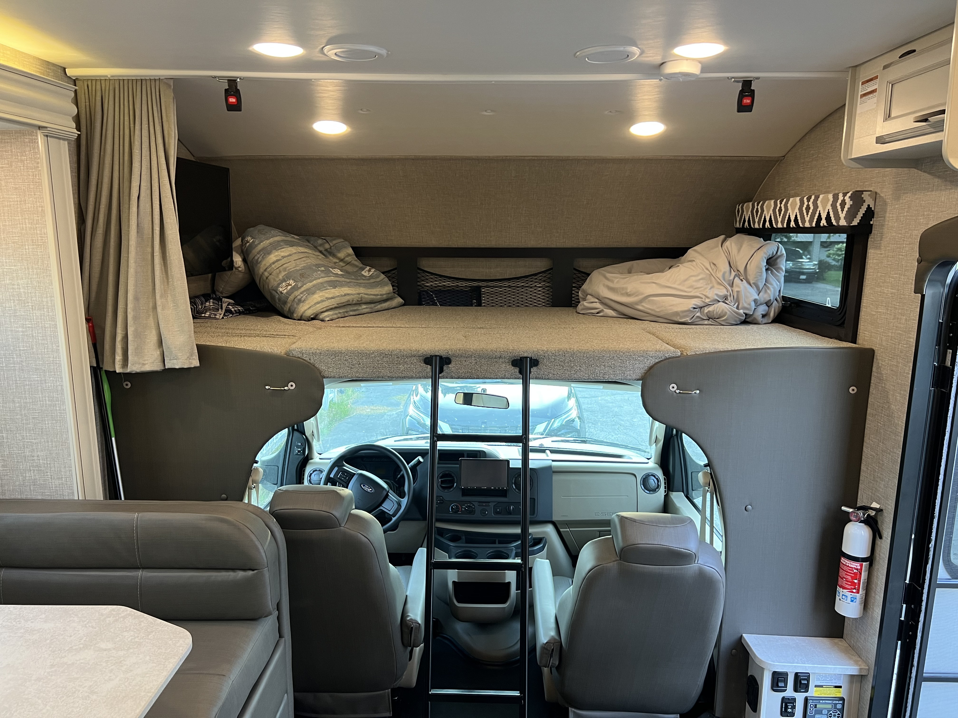 View inside an RV rental, showing the spacious overhead bunk bed, front cab, and a dinette area on the left.. Jayco Greyhawk 2022
