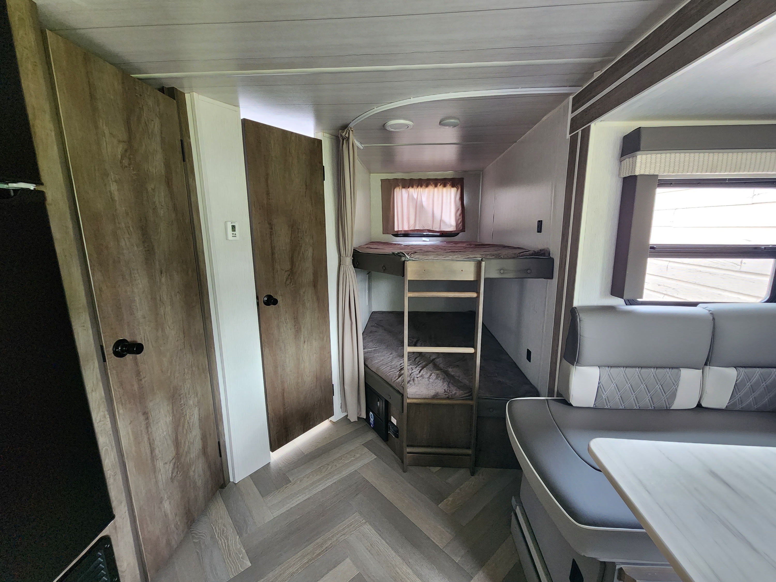 Inside an RV rental: view of bunk beds, dinette seating, and light wood-grain flooring, showing a compact, practical layout.. Forest River Other 2022