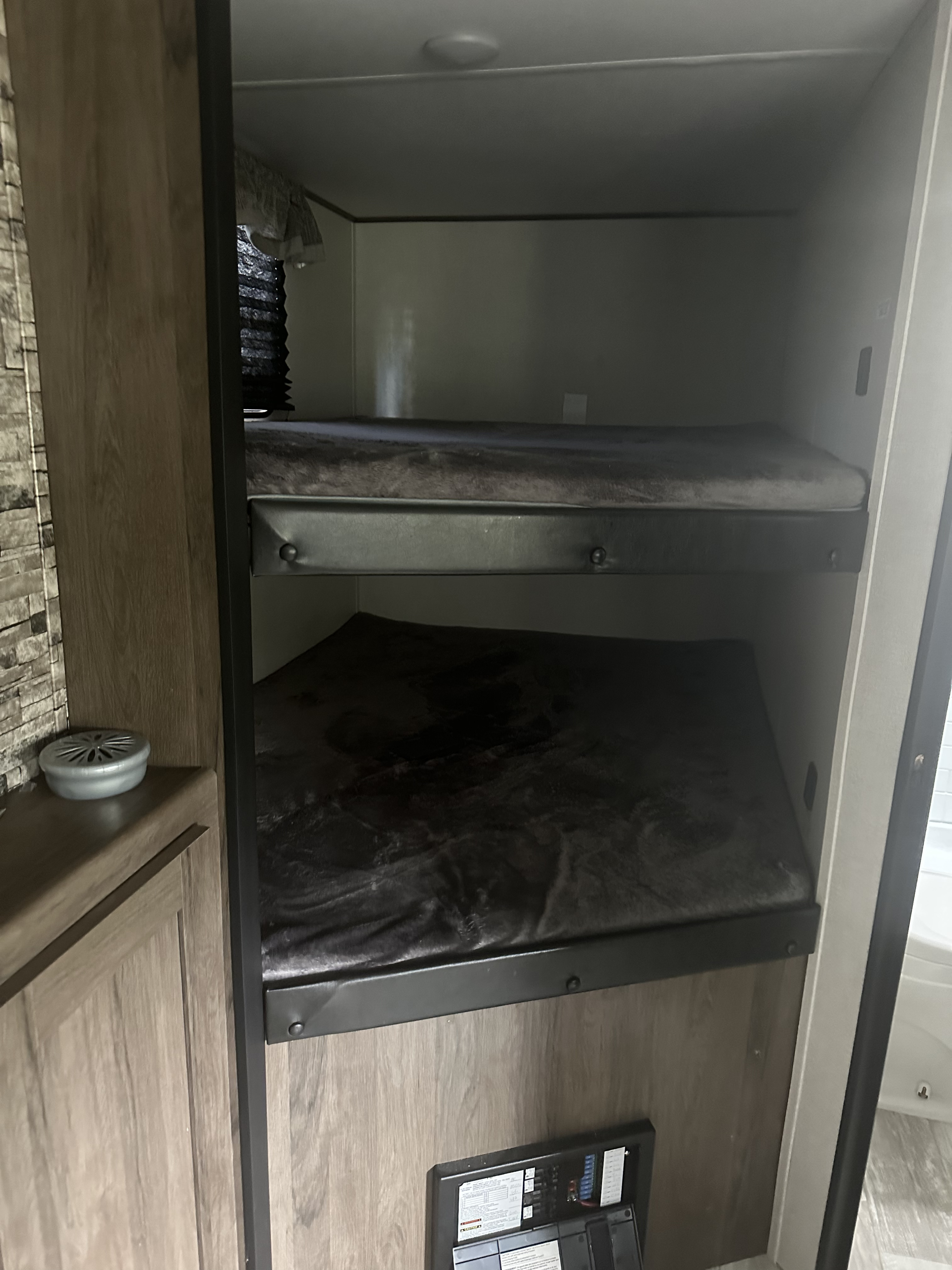 Interior view of an RV rental showing stacked bunk beds with soft dark mattresses & a power panel below.. Avenger Avenger Trailer 2021
