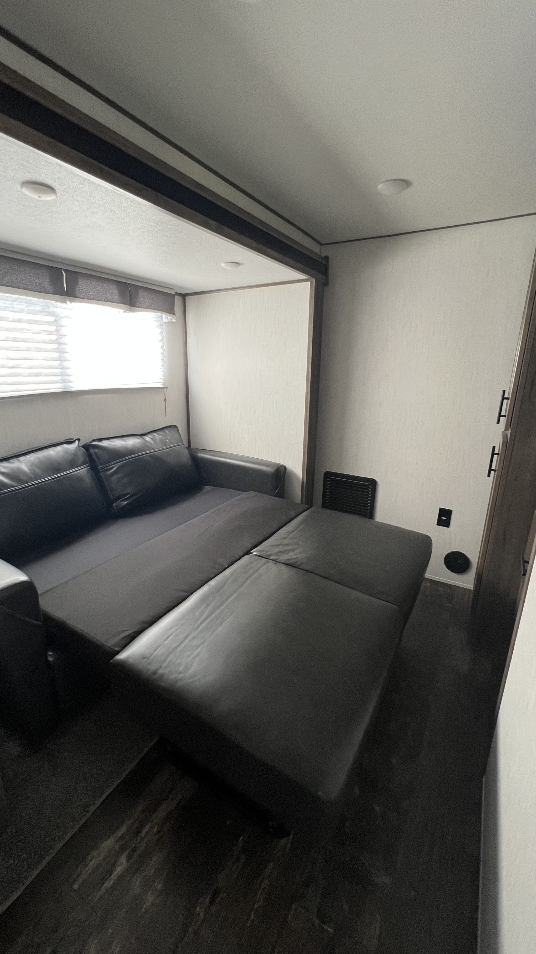 RV rental interior featuring a black faux leather sofa pulled out, converting into a comfortable bed for guests.. Forest River Sabre 2021