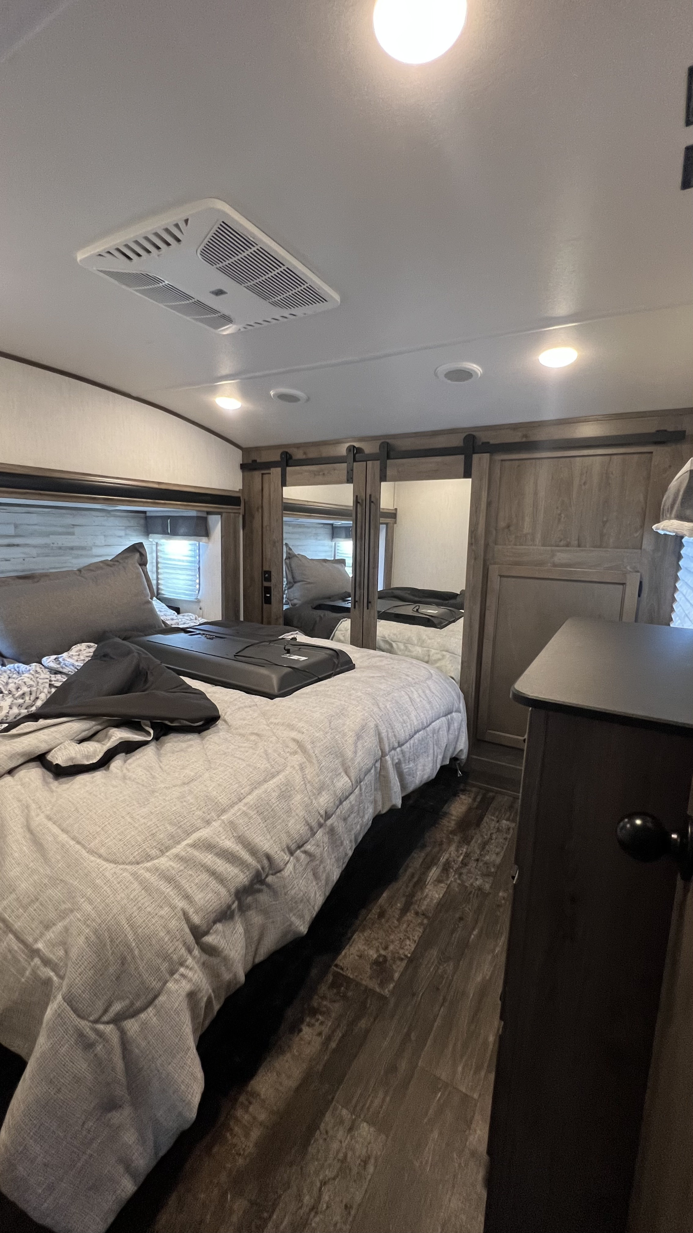 Compact RV rental bedroom featuring a cozy bed, ceiling AC unit, and stylish sliding closet doors.. Forest River Sabre 2021
