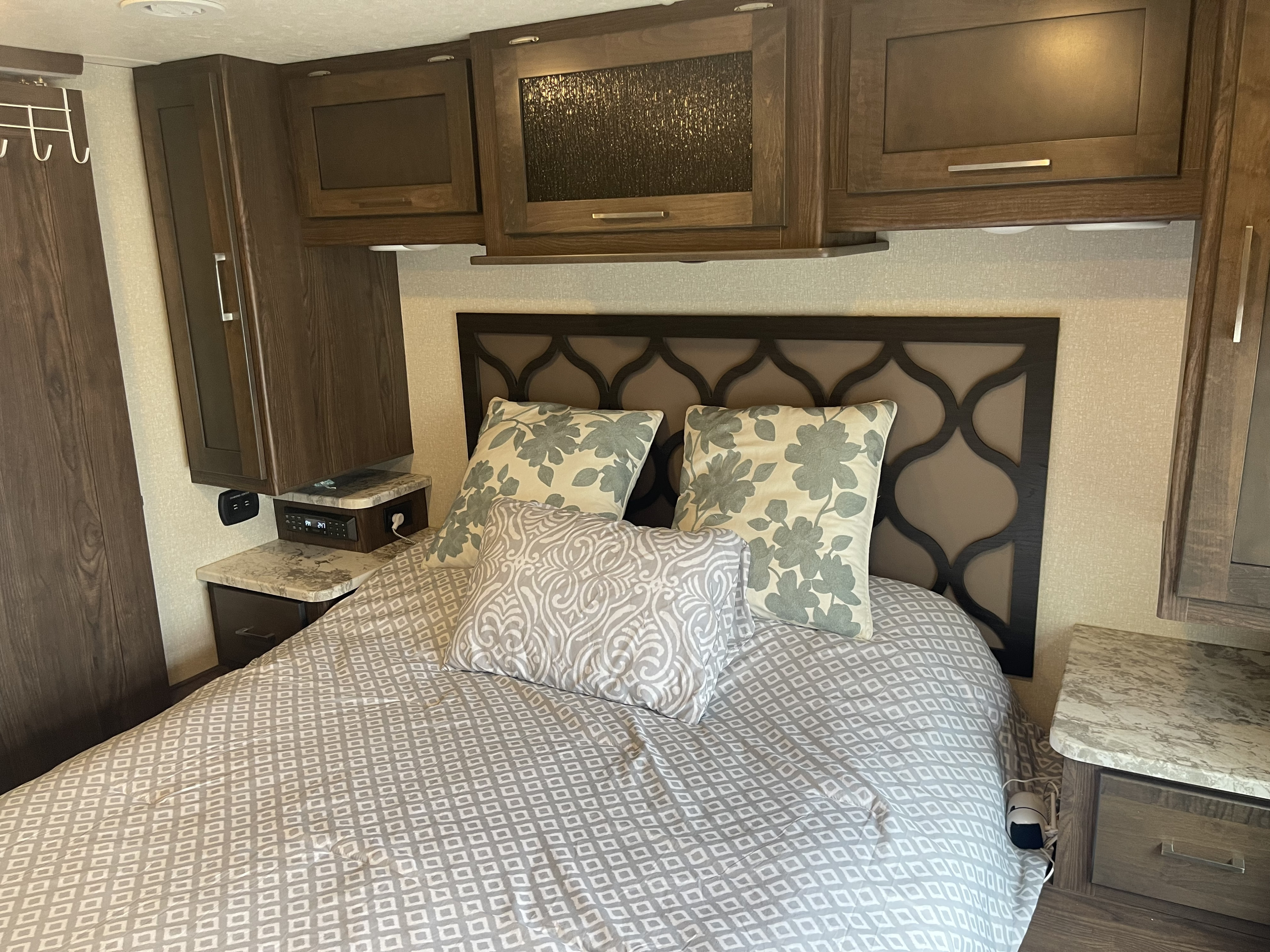 RV rental bedroom setup: patterned bed, stylish headboard, practical overhead cabinets, and bedside charging.. Pursuit 29SSP 2020