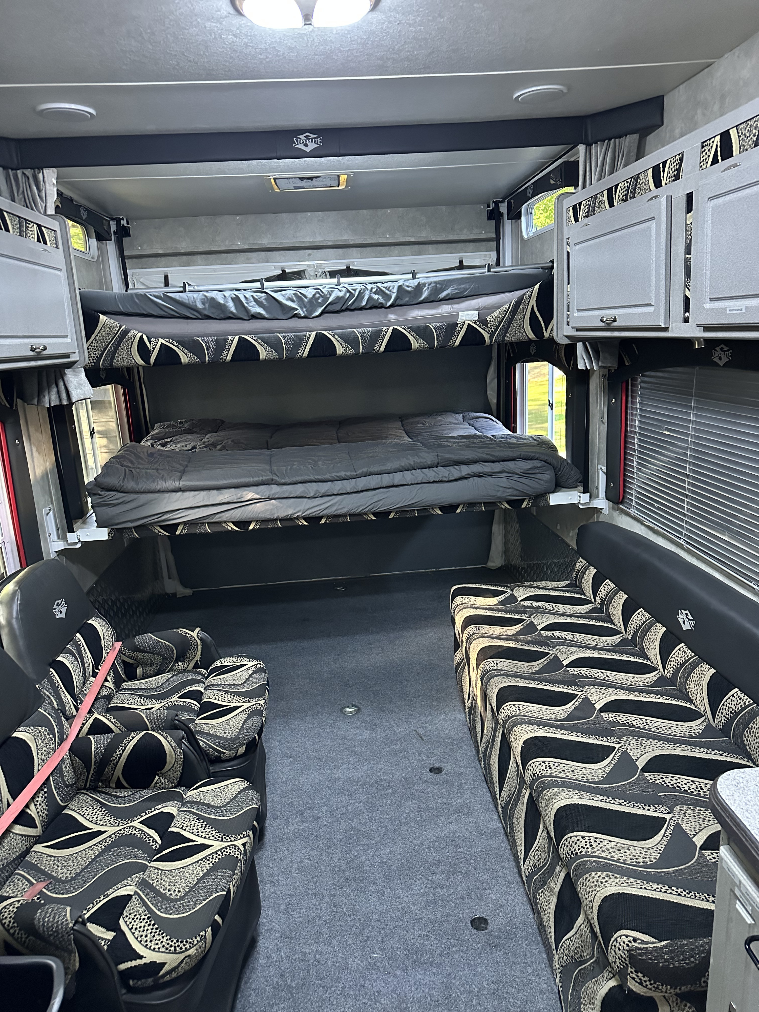 RV rental interior featuring elevated bunk beds, patterned sofas, and overhead storage.. Weekend Warrior 2600fs 2008