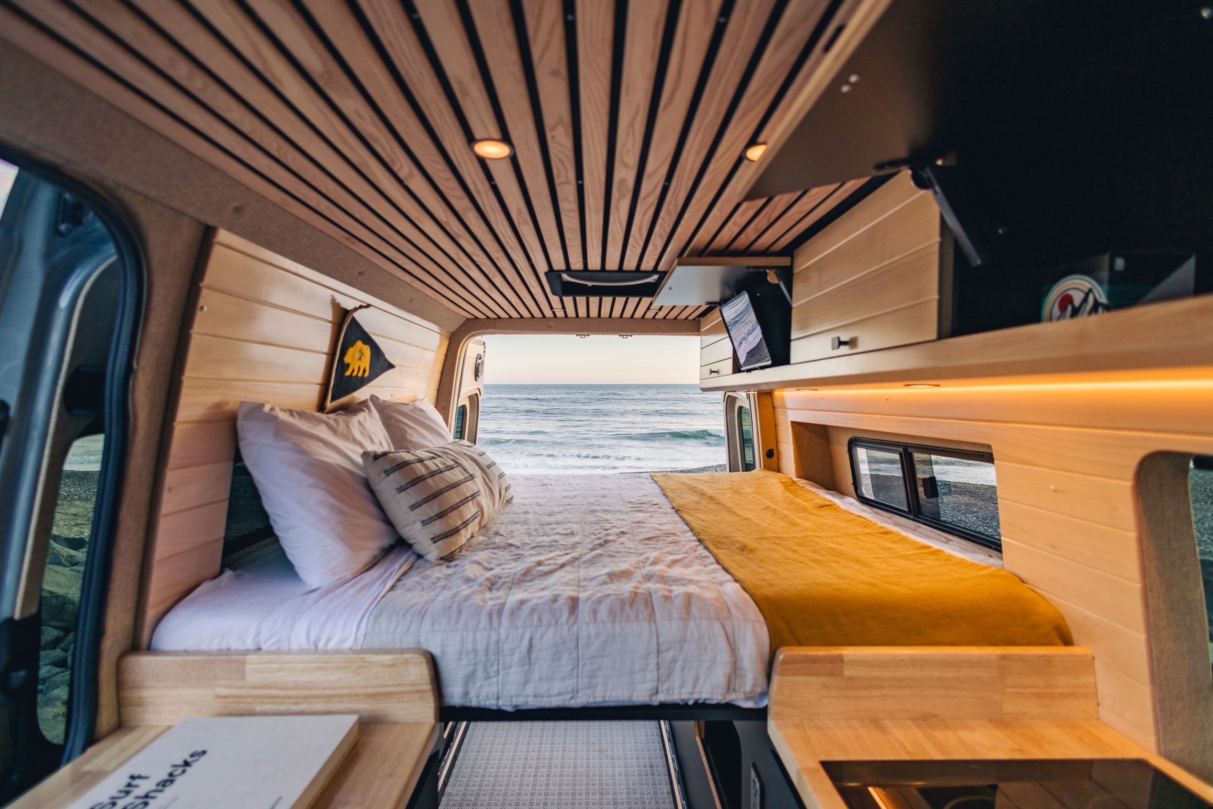 RV rental: Plush camper van interior with a cozy bed, opening to a stunning ocean view. Perfect for beach adventures.. Mercedes-Benz Sprinter 2023