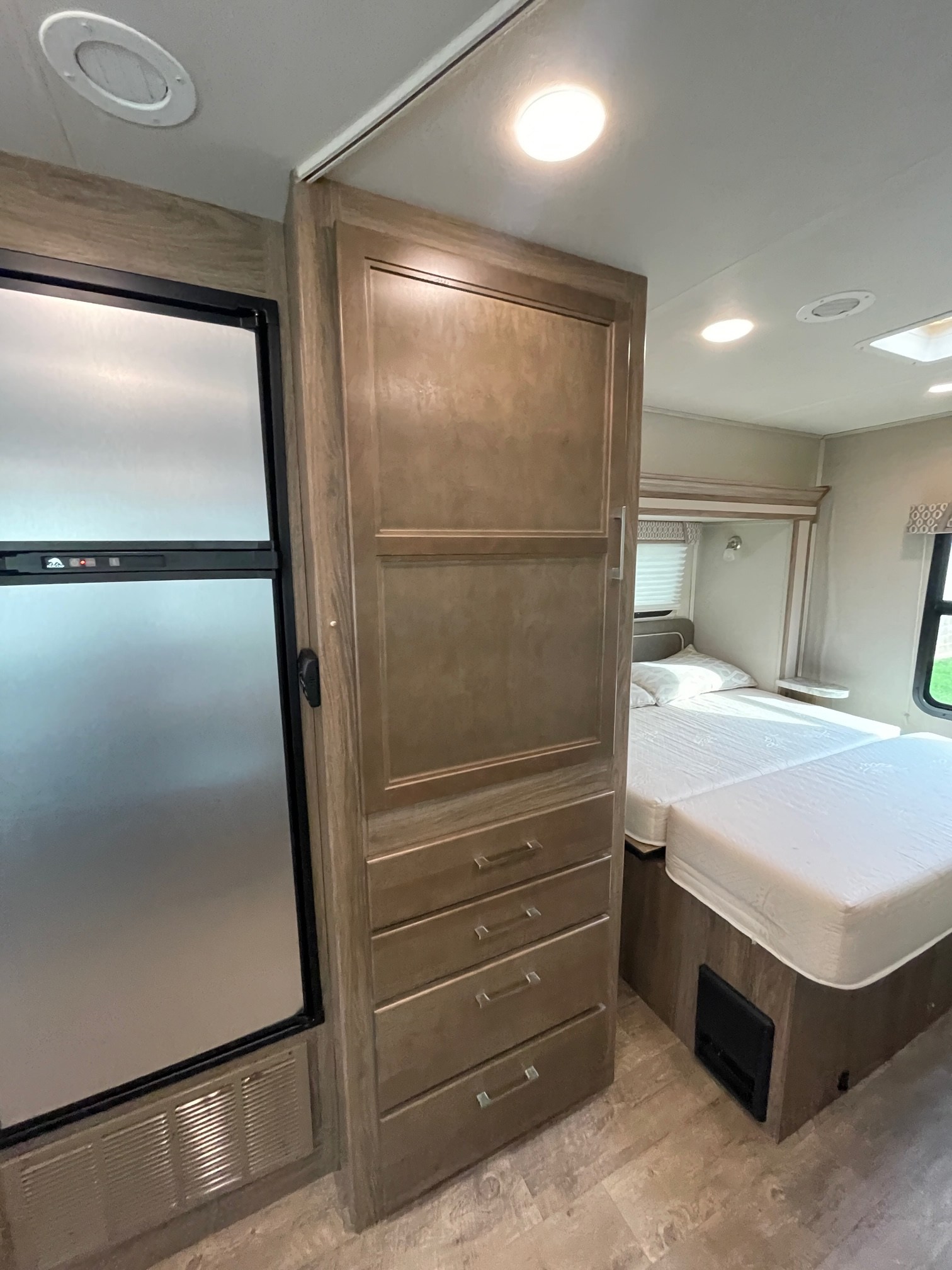 RV rental interior featuring a modern fridge, ample storage cabinetry, and a comfortable bedroom setup.. Entegra Coach Odyssey 2018