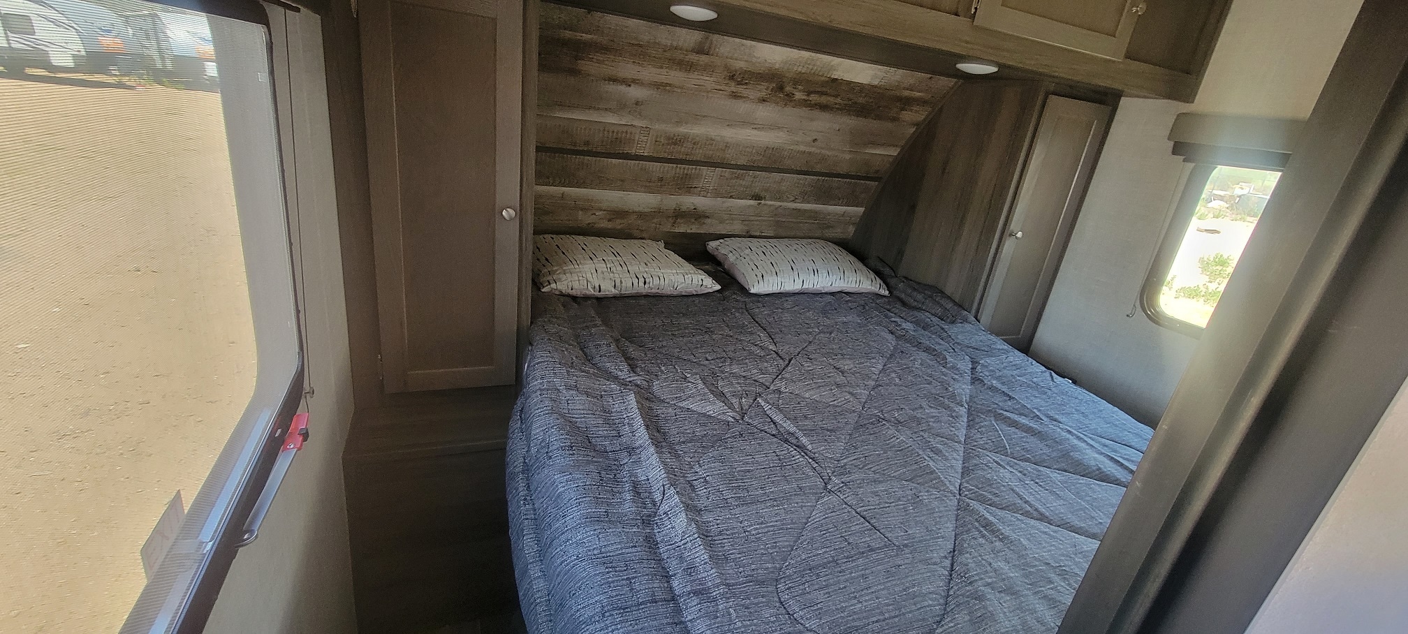 Spacious RV rental bedroom featuring a comfortable bed, stylish wood headboard, and convenient cabinet storage.. Gulf Stream Gulf Breeze 2023