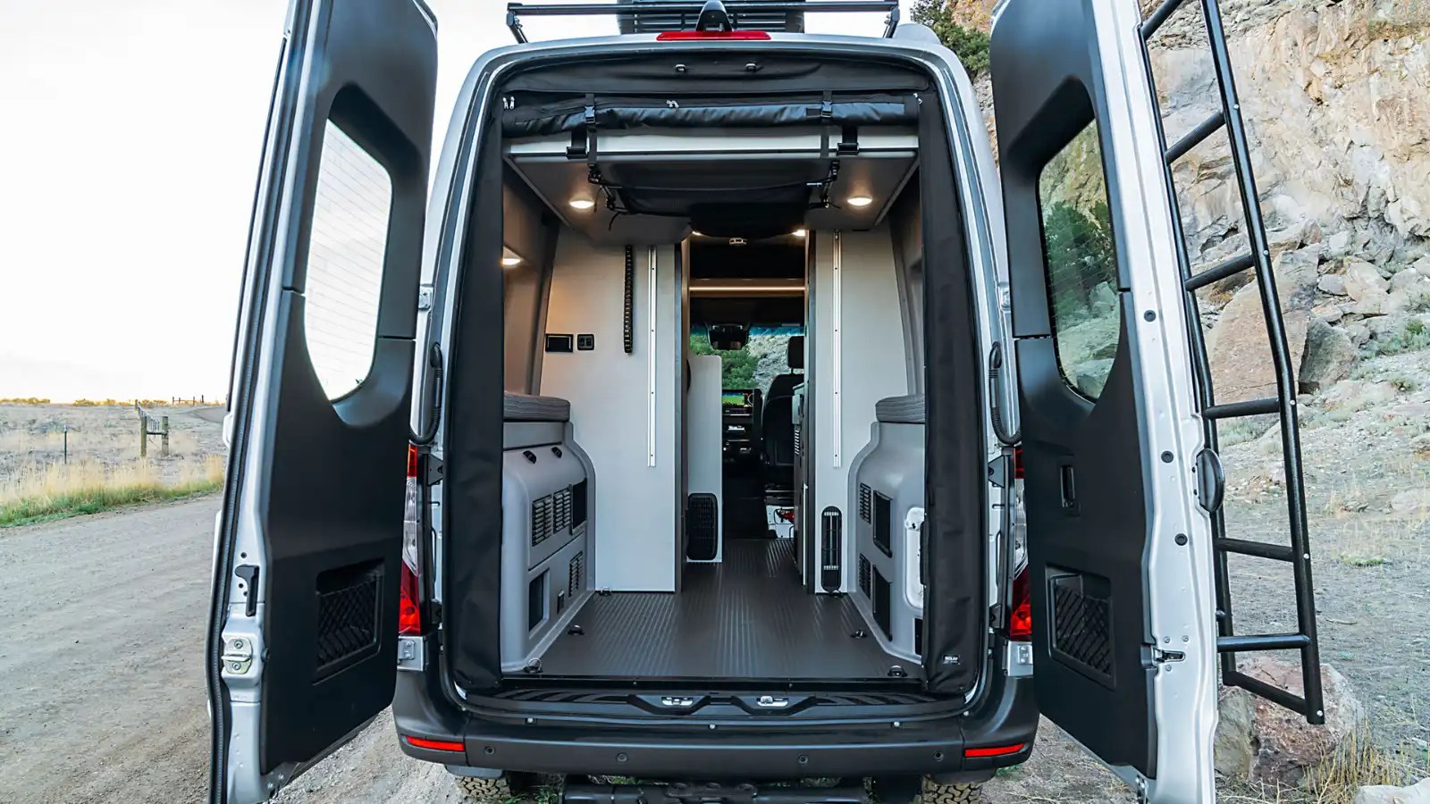 Spacious RV rental interior with open rear doors, a roof access ladder, and organized storage for adventures.. Winnebago Revel 2021