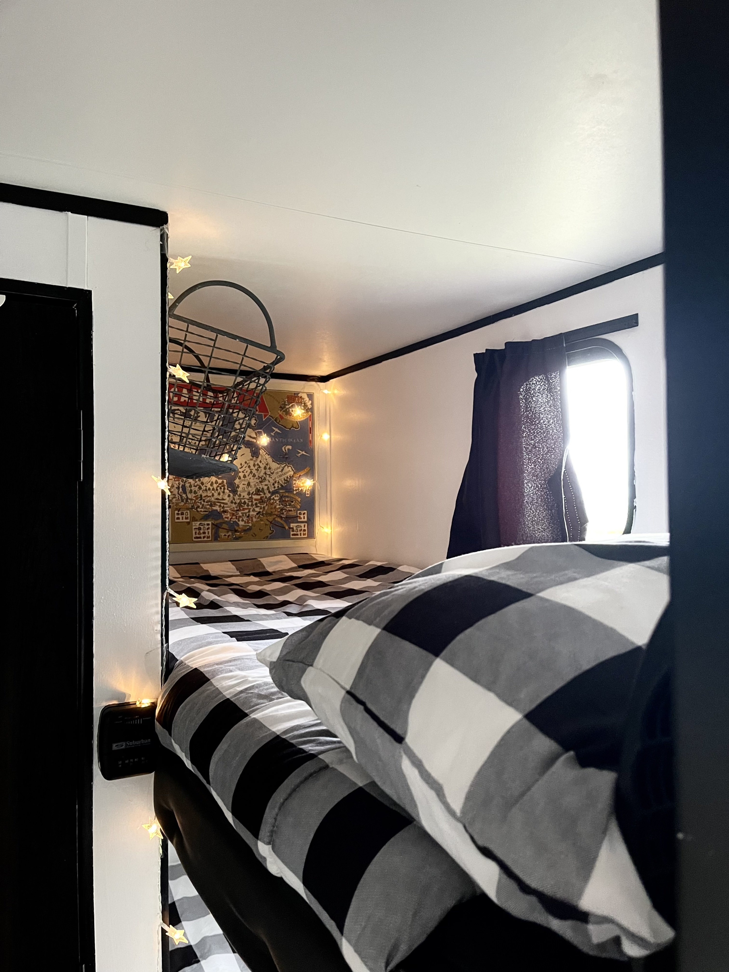 This RV rental's cozy bunk features black & white buffalo check bedding, map art, & charming star string lights.. Jayco Jay Flight SLX 2022