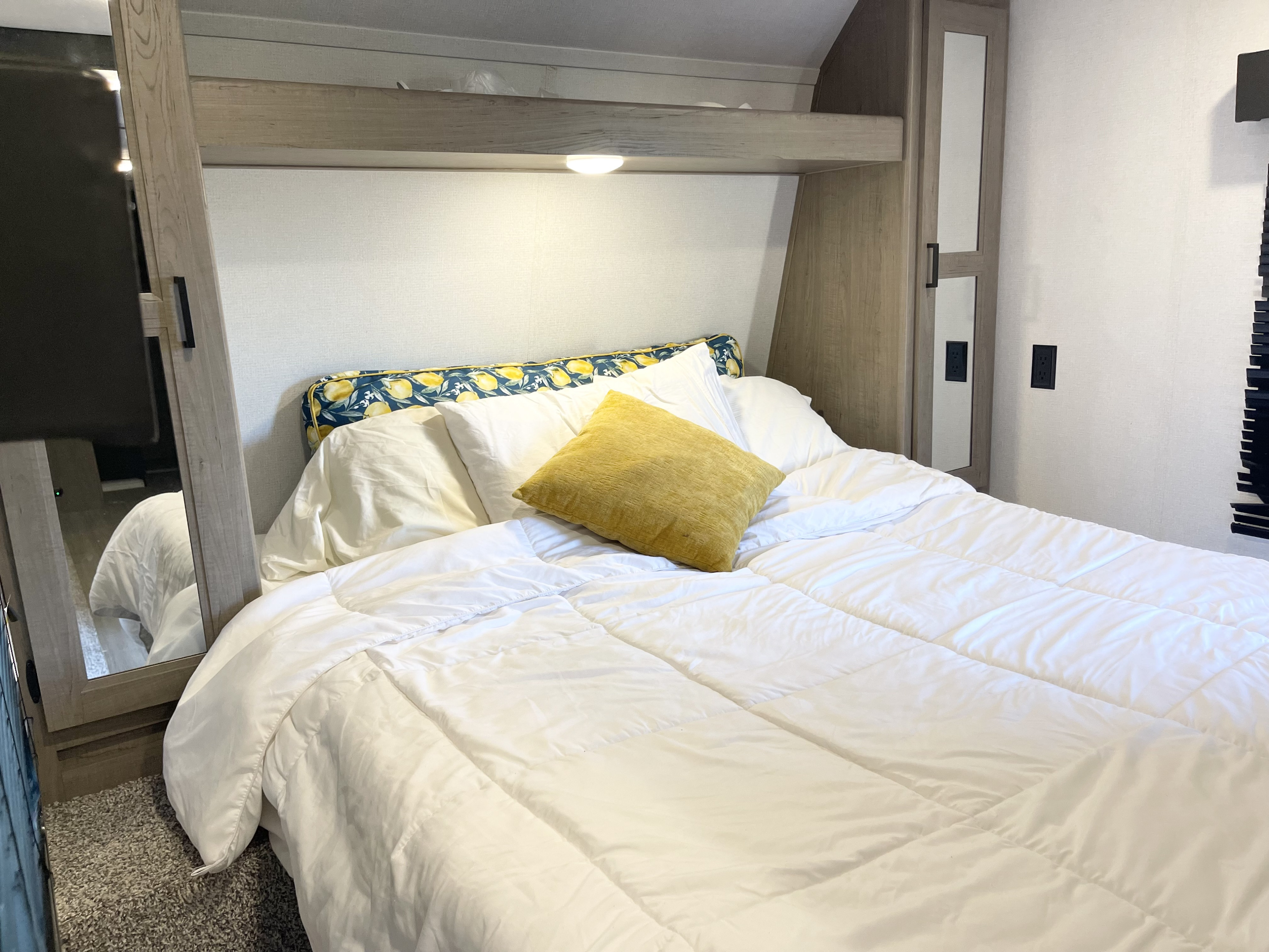 Experience comfort in this RV rental bedroom: white bed, lemon headboard, and mirrored cabinet.. Keystone RV Hideout LHS 2020