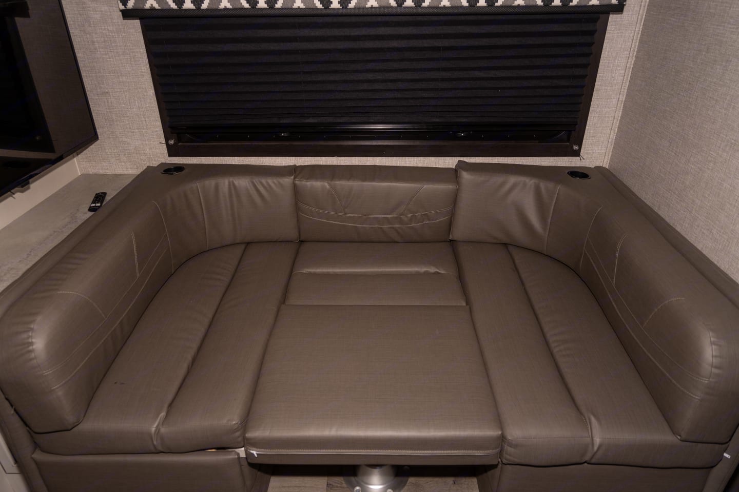 Comfortable U-shaped dinette with brown cushions, cup holders, and window shade for your RV rental.. Jayco Redhawk 2022