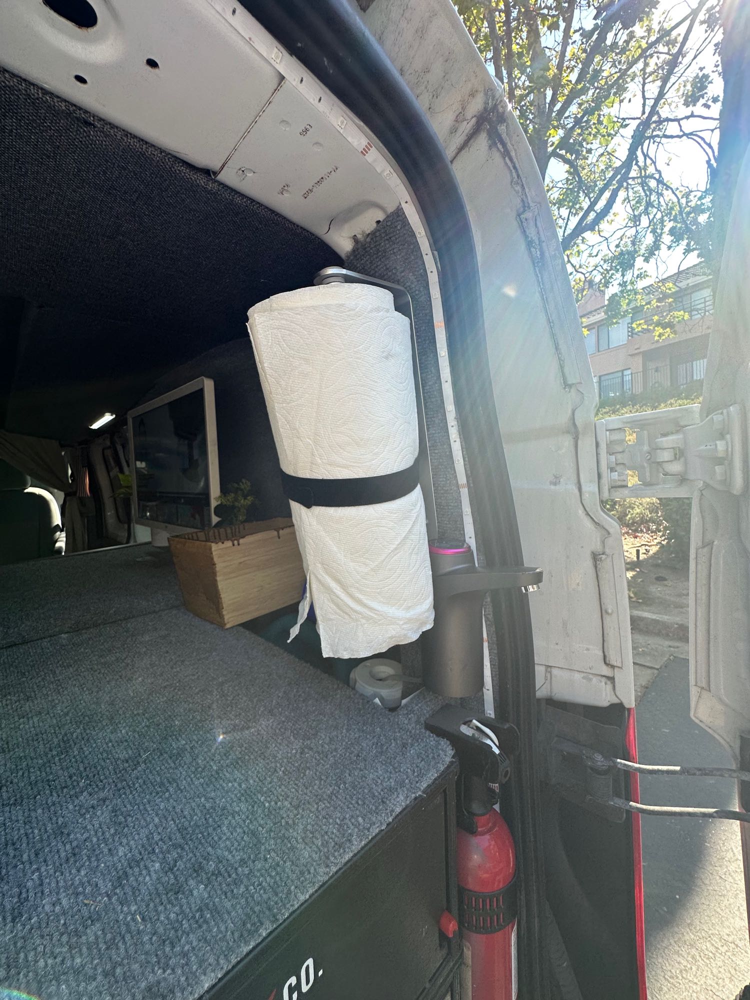 RV rental interior: Secured paper towels & fire extinguisher near open door, showcasing an organized van setup.. Ford Transit 2016