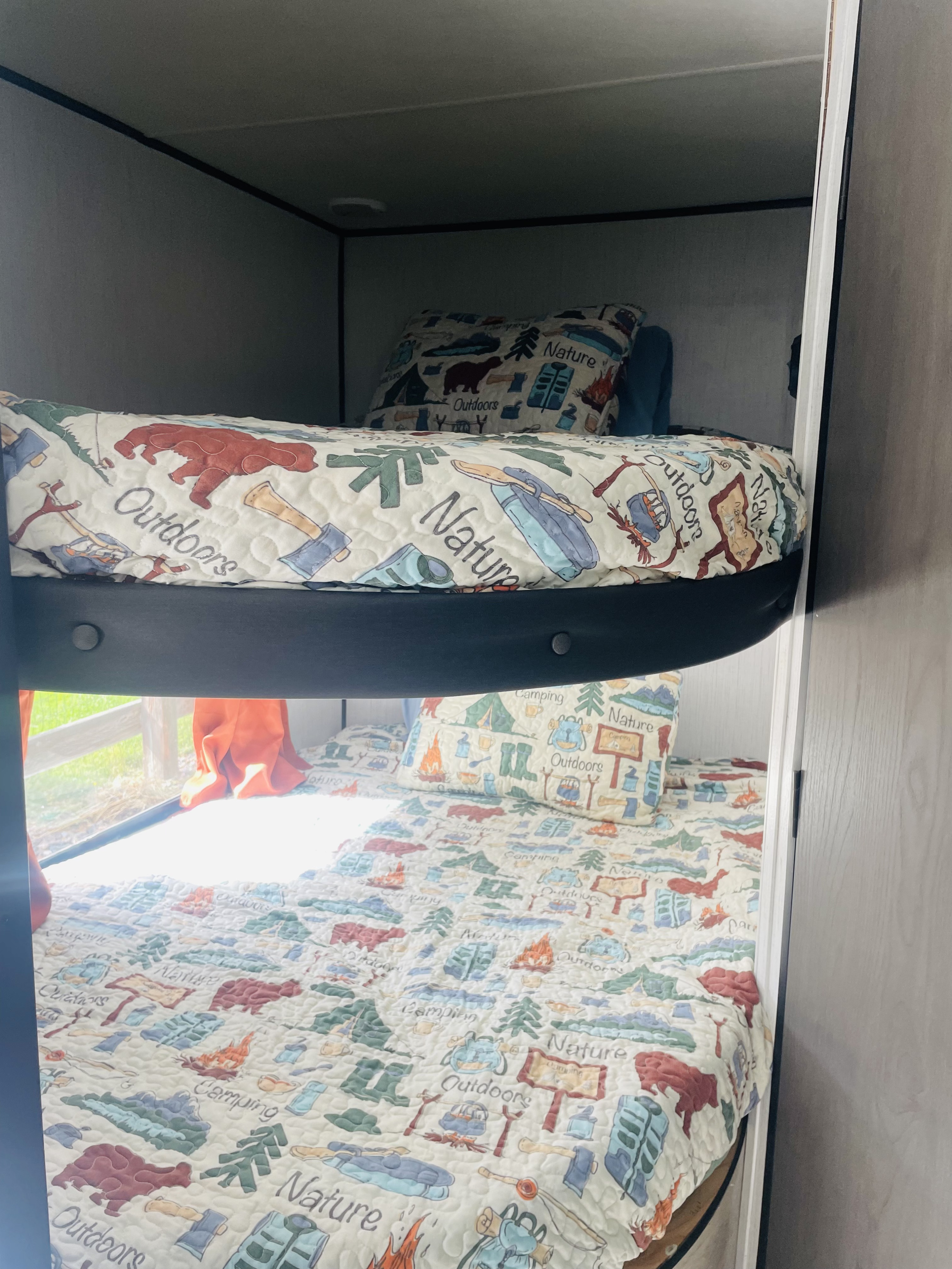 Inside an RV rental: comfortable bunk beds with playful camping and nature designs. Great for kids!. Heartland RVs Prowler 2022