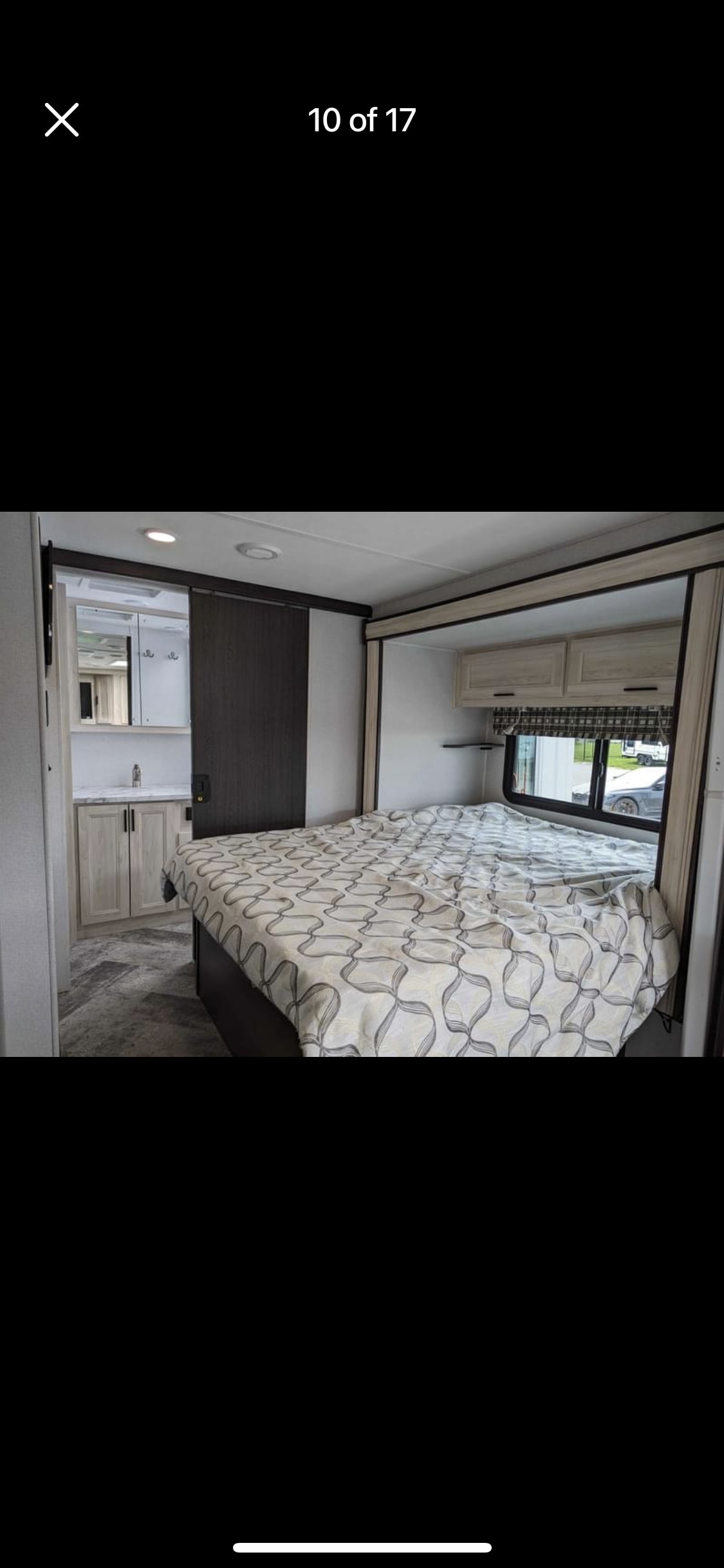 Cozy RV rental bedroom features a patterned bed, overhead cabinets, and a vanity area with a sink.. Forest River Sunseeker Classic 2021