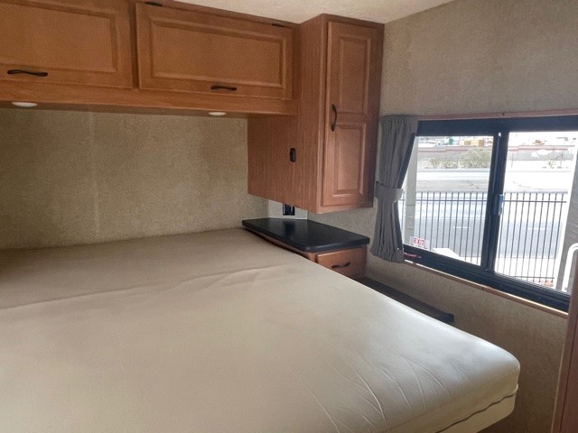 RV rental interior: comfortable sleeping area with bed, wood cabinets, and a large window for travel.. Thor Majestic 2018