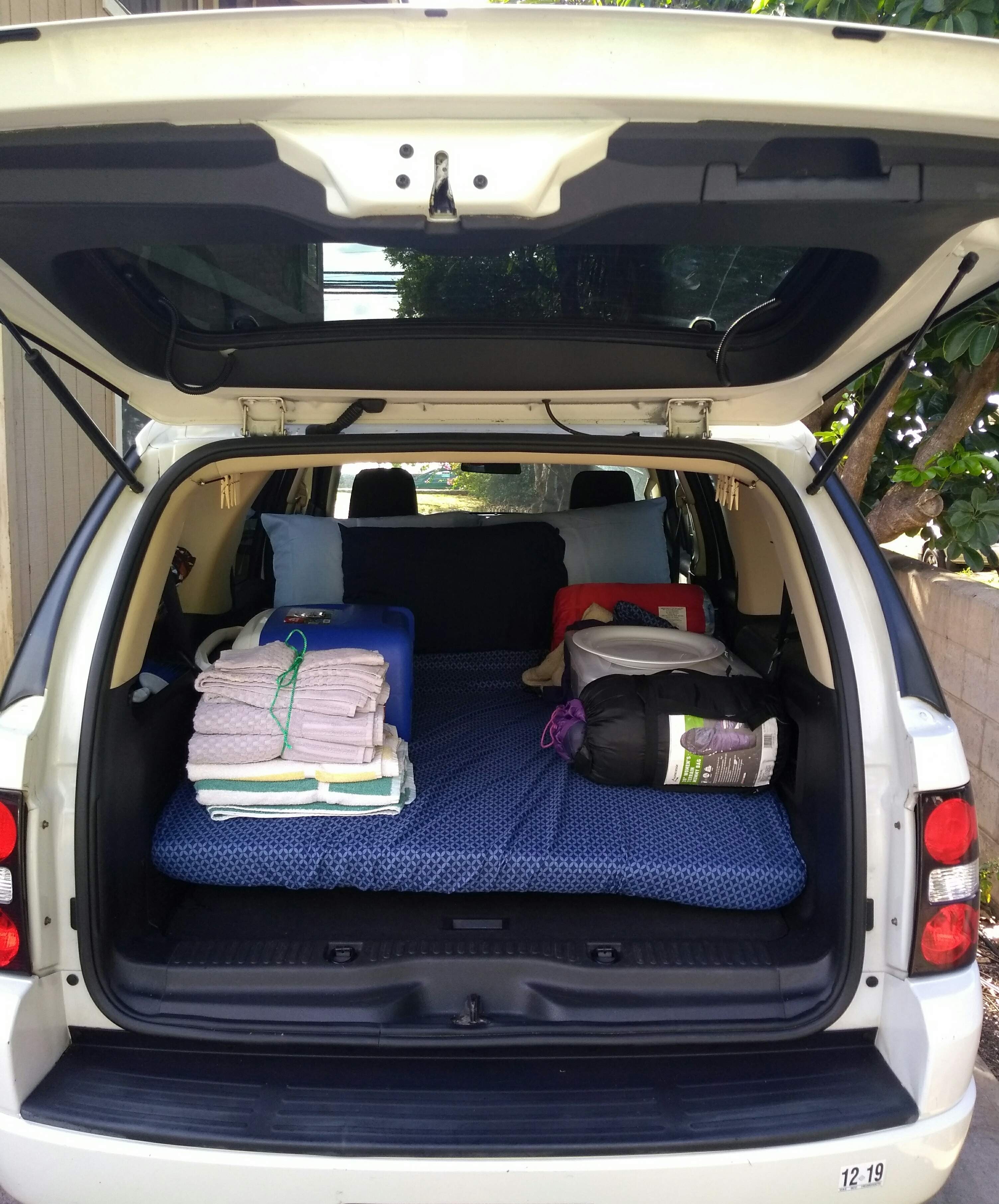 White SUV trunk showing a sleeping setup with mattress & sleeping bag – a smart alternative to an RV rental for car camping.. Xplorer Explorer 2007