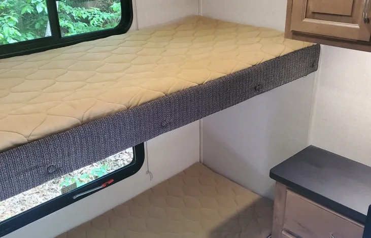 Inside an RV rental: cozy bunk beds, lower mattress, window view, and cabinetry.. Forest River Coachmen Chapparal Lite 2019