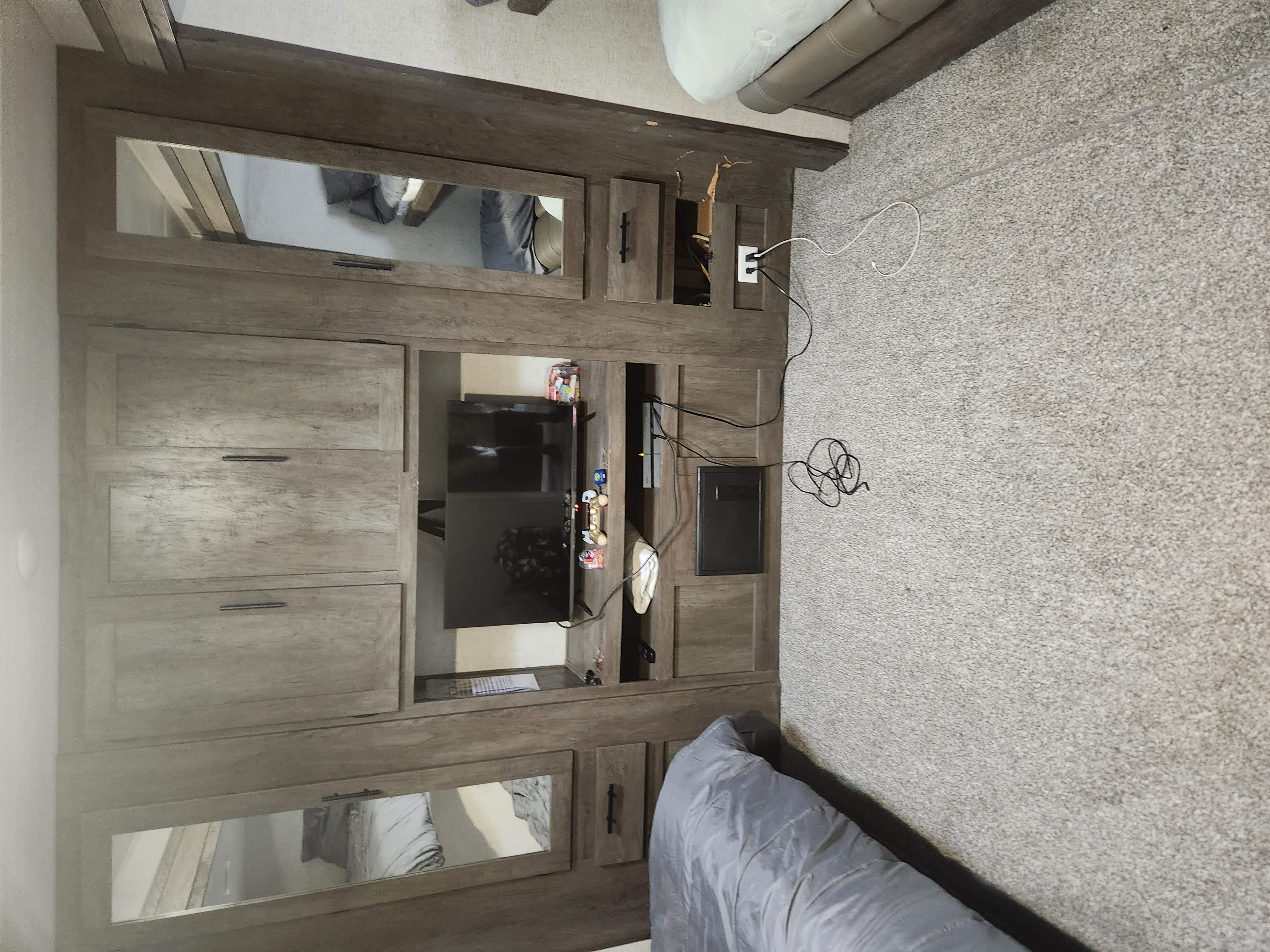 View of an RV rental's cozy interior, featuring a wood entertainment center with TV, ample storage, and carpeted floor.. Forest River Salem 2021