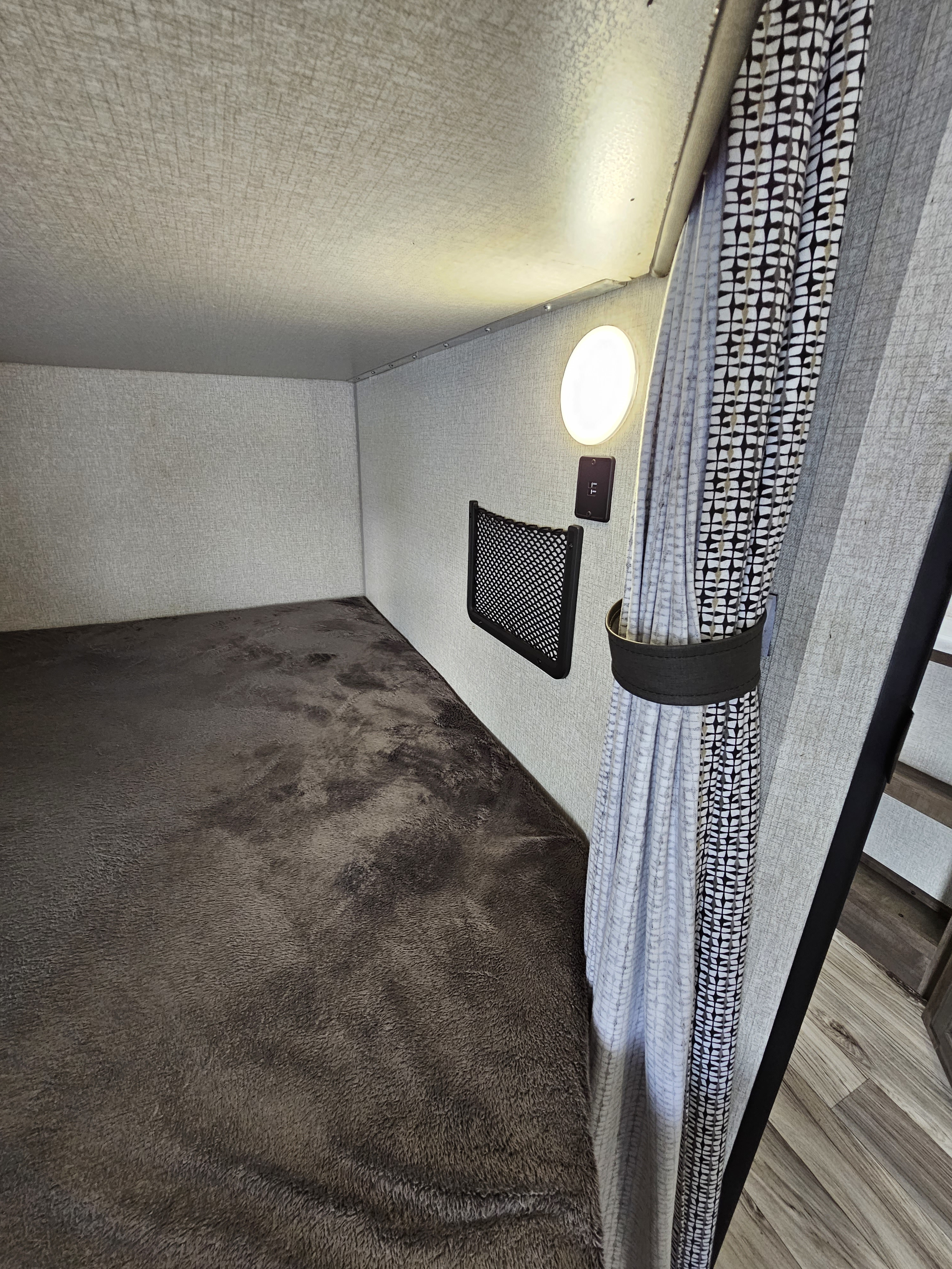 RV rental bunk bed features: plush mattress, light, charging port, net storage, and stylish curtain.. Venture Stratus 2022