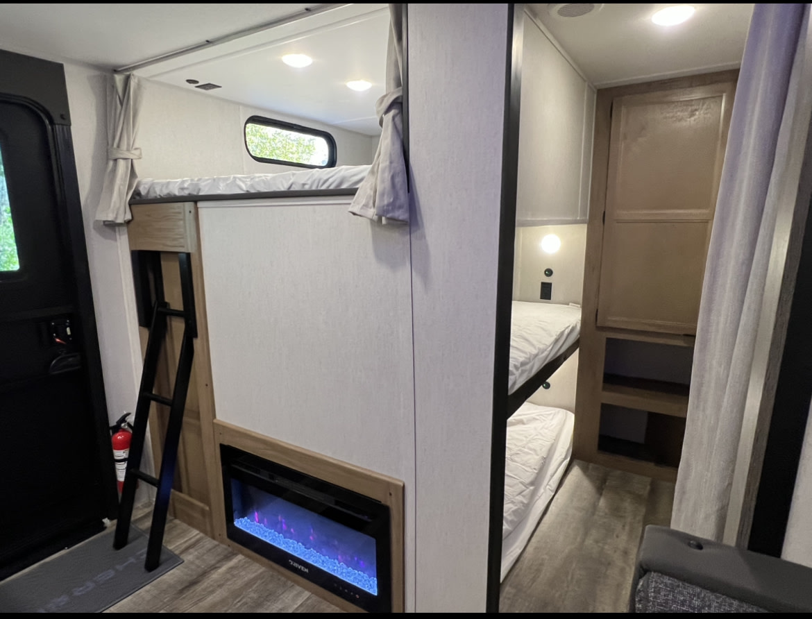 An rv rental offers compact comfort: bunk beds, ladder, electric fireplace, and cabinet storage.. Forest River Cherokee 2024