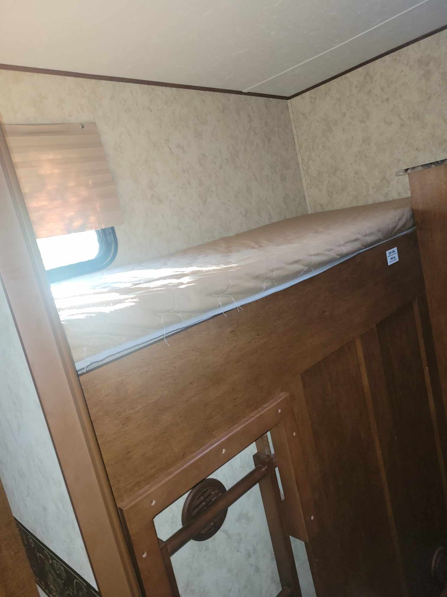 RV rental interior featuring a wooden bunk bed with a mattress, window, and patterned walls.. Forest River Coachmen 2012